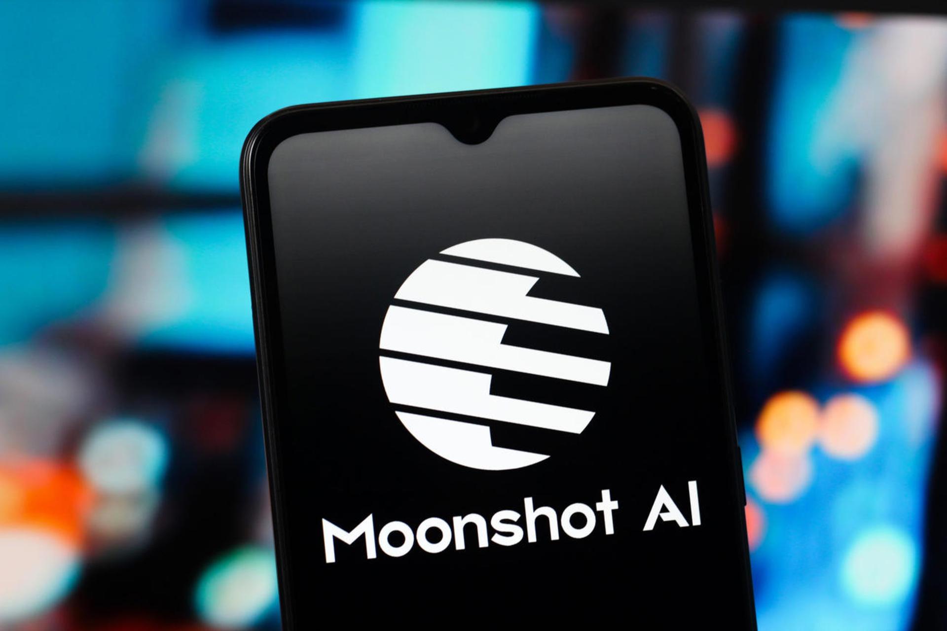 نمای نزدیک از لوگوی سفید رنگ شرکت Moonshot AI روی صفحه نمایش یک گوشی هوشمند با پس‌زمینه تار