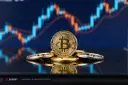 سکه طلایی بیت‌کوین (Bitcoin) روی سطحی بازتابنده در مقابل نمودار قیمت