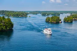 قایق تفریحی سفید در میان جزایر کوچک دریاچه انتاریو (Lake Ontario)