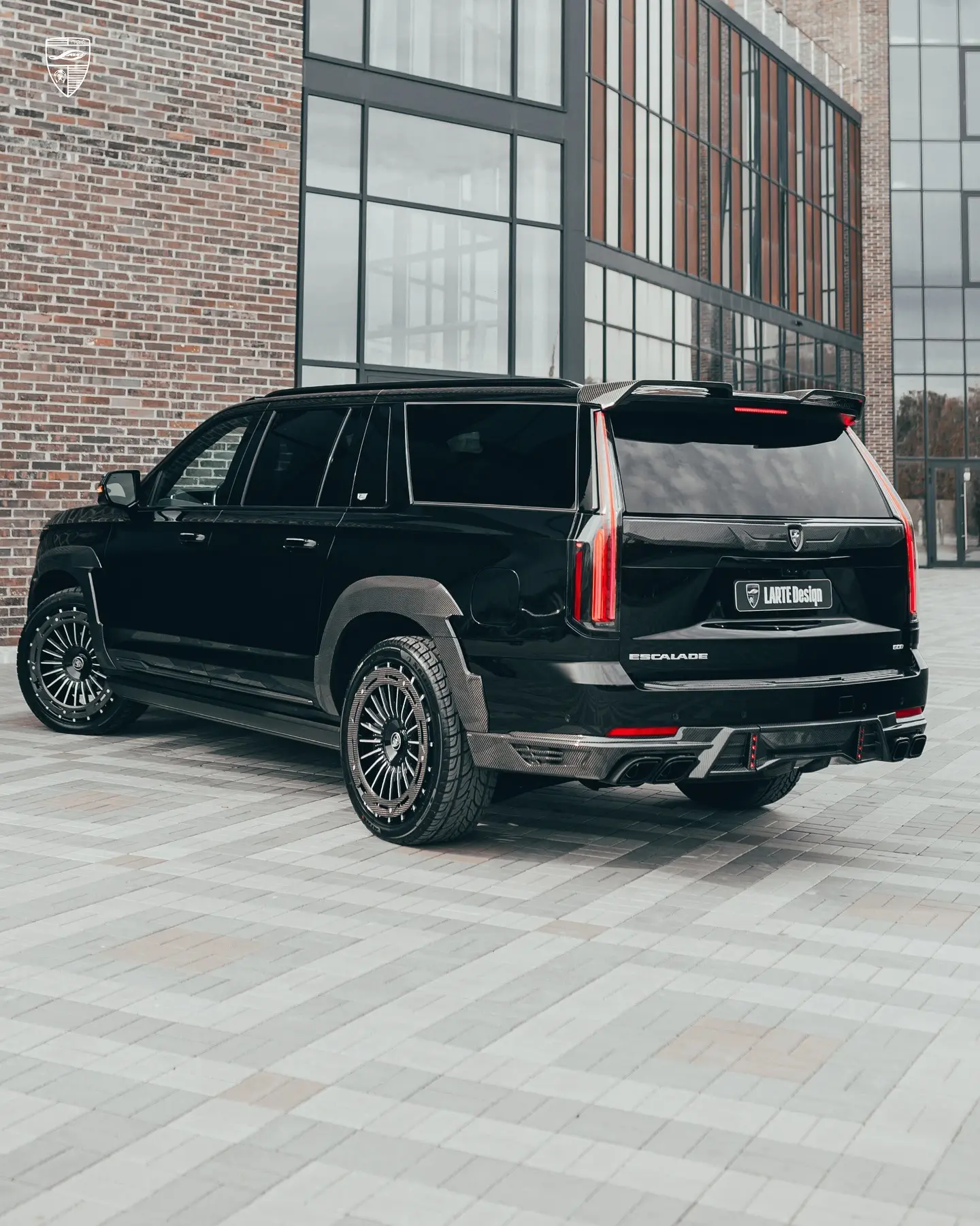 کادیلاک اسکالید (Cadillac Escalade) با بدنه مشکی و رینگ‌های سفارشی در مقابل ساختمان مدرن