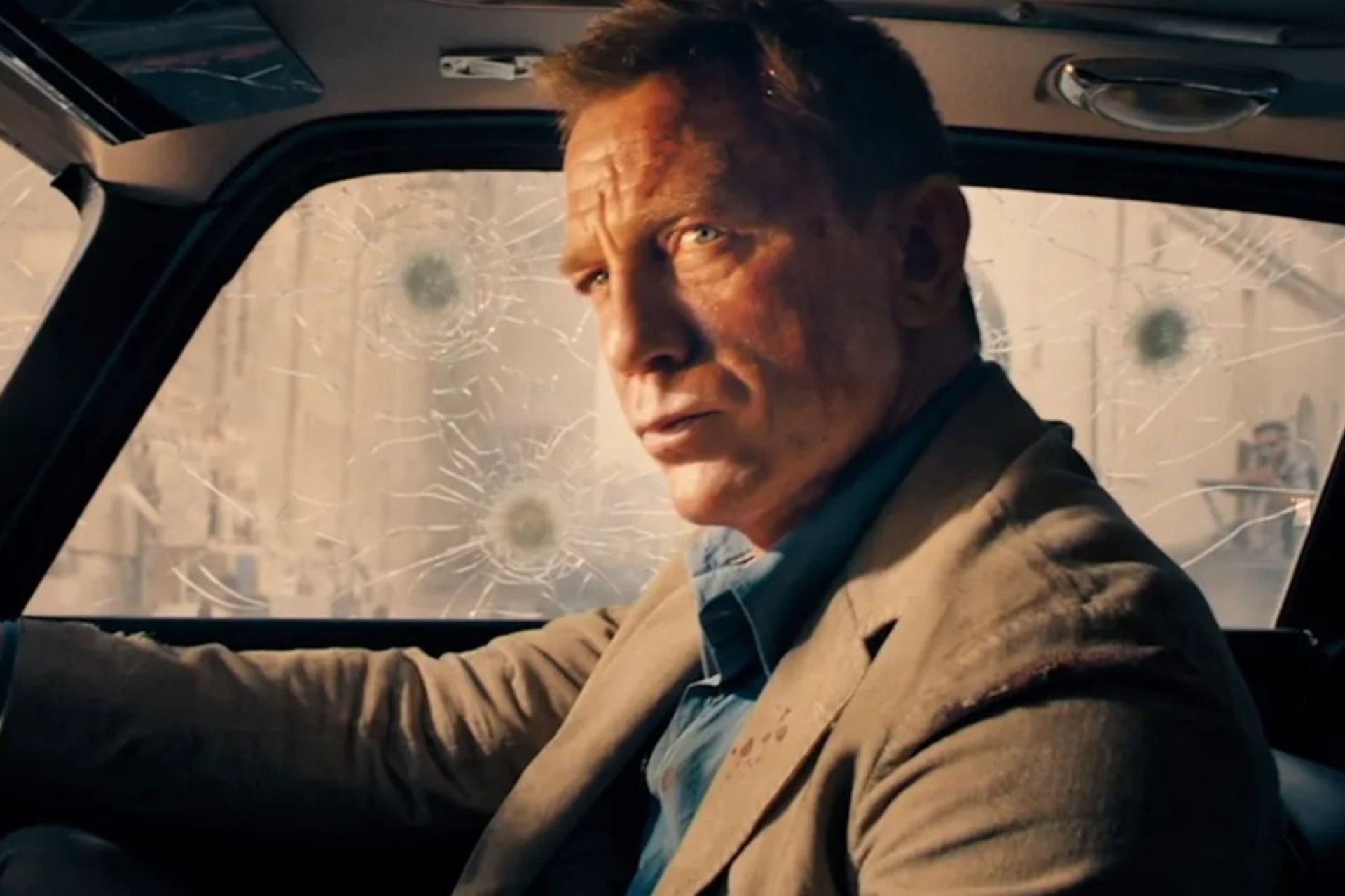 یک مرد با کت قهوه‌ای درون خودرو ضدگلوله