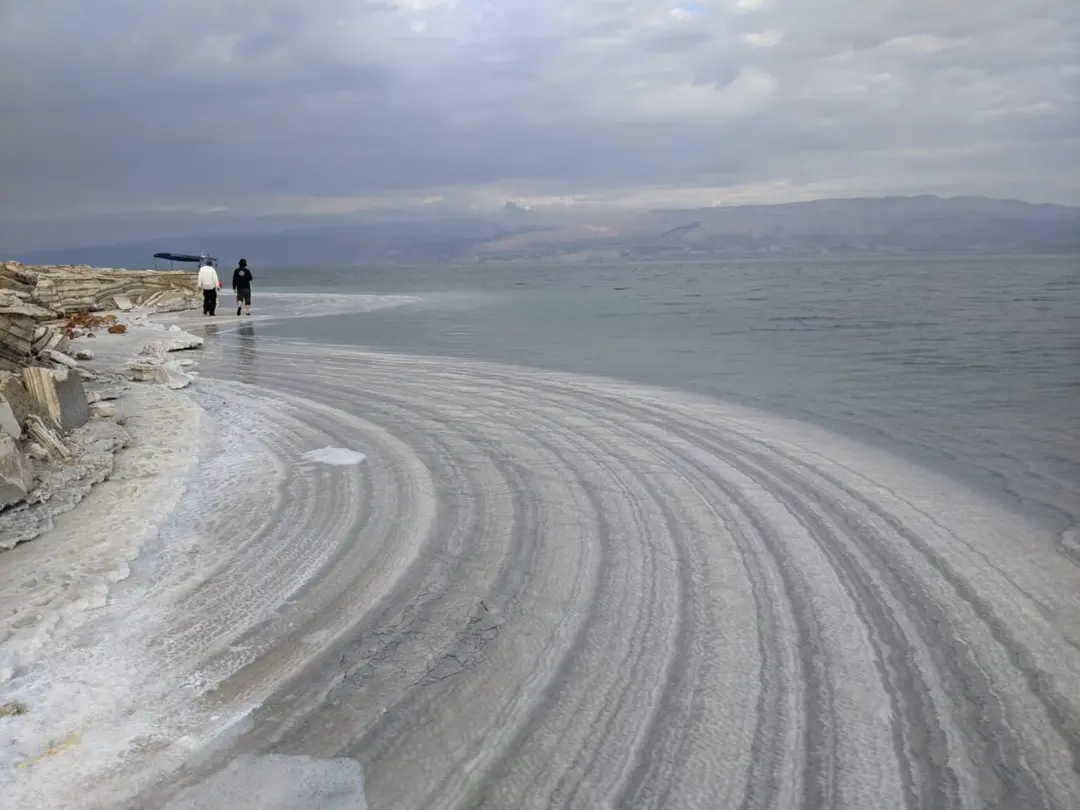 لایه‌های نمک سفید در ساحل دریای مرده (Dead Sea) کنار آب