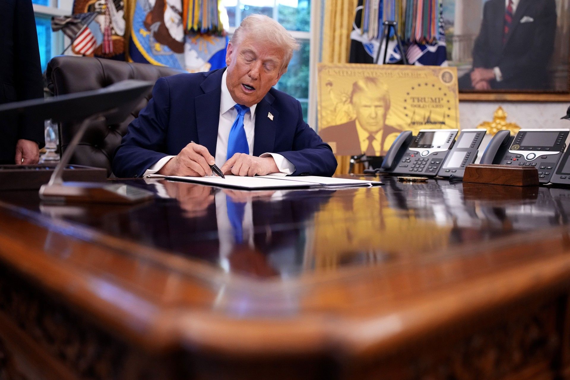 رئیس‌جمهور آمریکا پشت میز در حال امضای یک فرمان