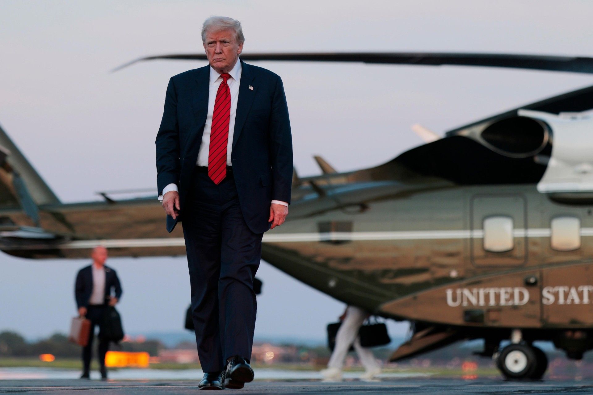 یک مرد با کت‌وشلوار در حال راه‌رفتن در باند فرود هلیکوپتر