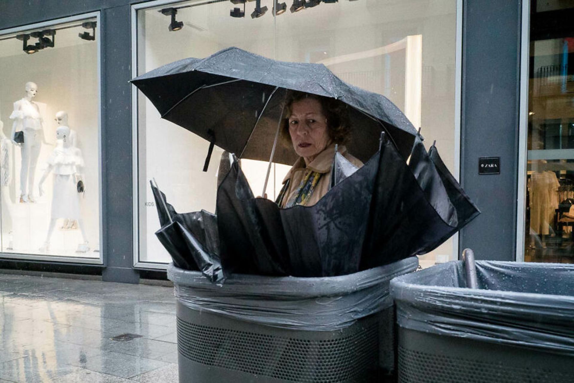 زنی با چتر سیاه به چتر سیاهی در زباله ها نگاه میکند