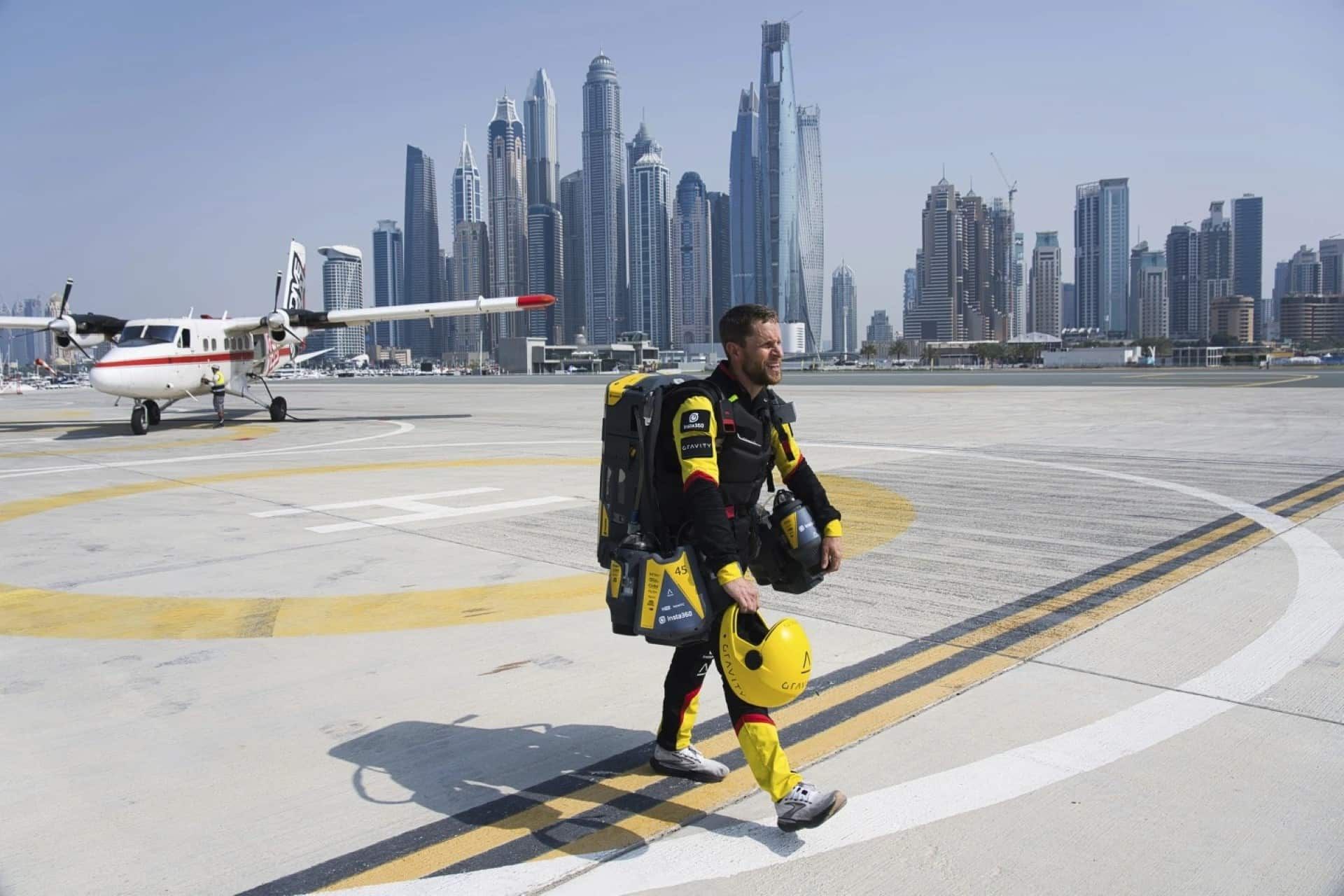 ریچارد براونینگ با لباس جت‌پک زد روی باند هواپیما - پس زمینه‌ی آسمان خراش‌های دبی