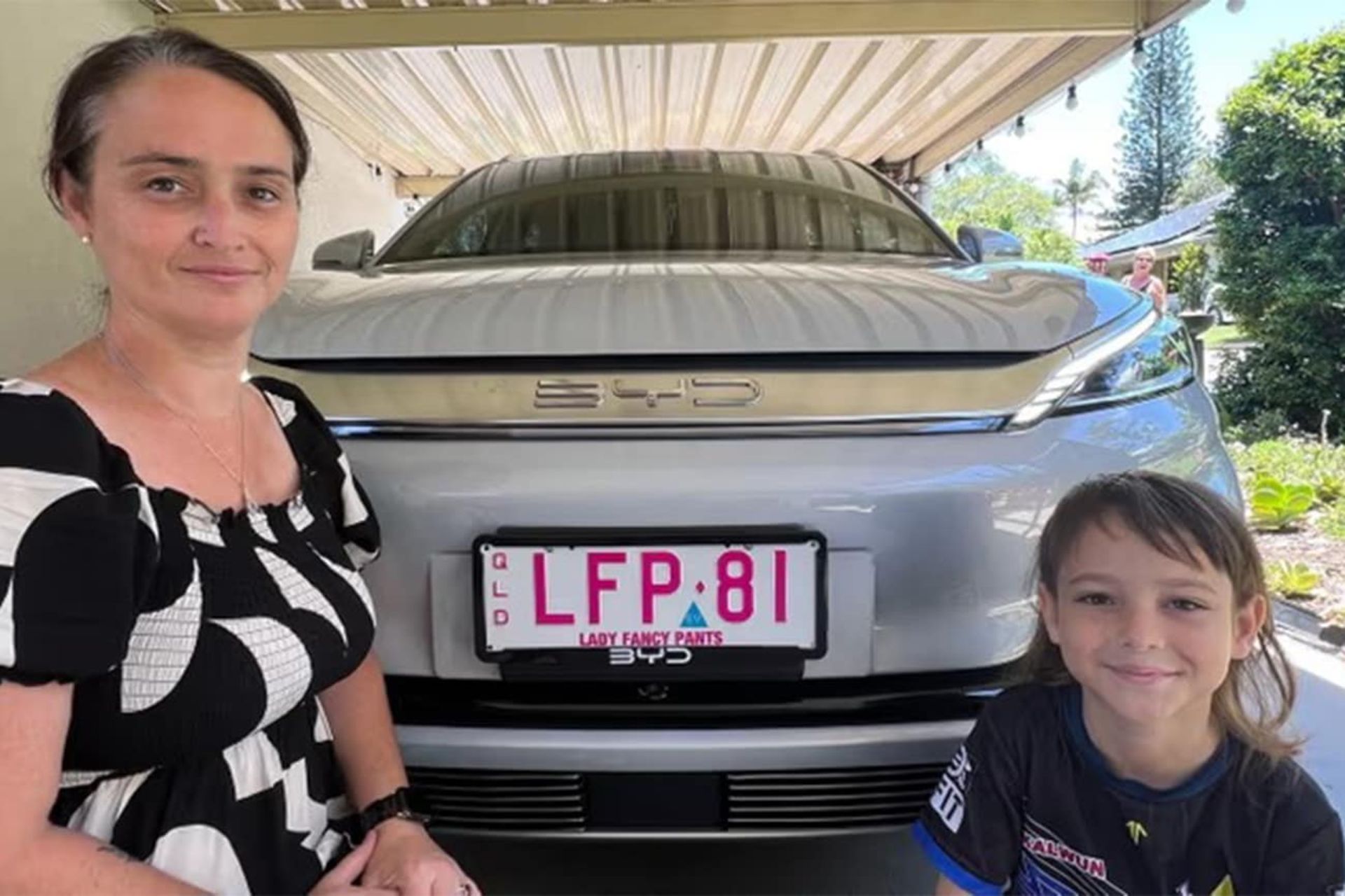 خودروی برقی بی وا دی اوتو ۳ نقرهای رنگ پشت یک زن و یک پسر بچه