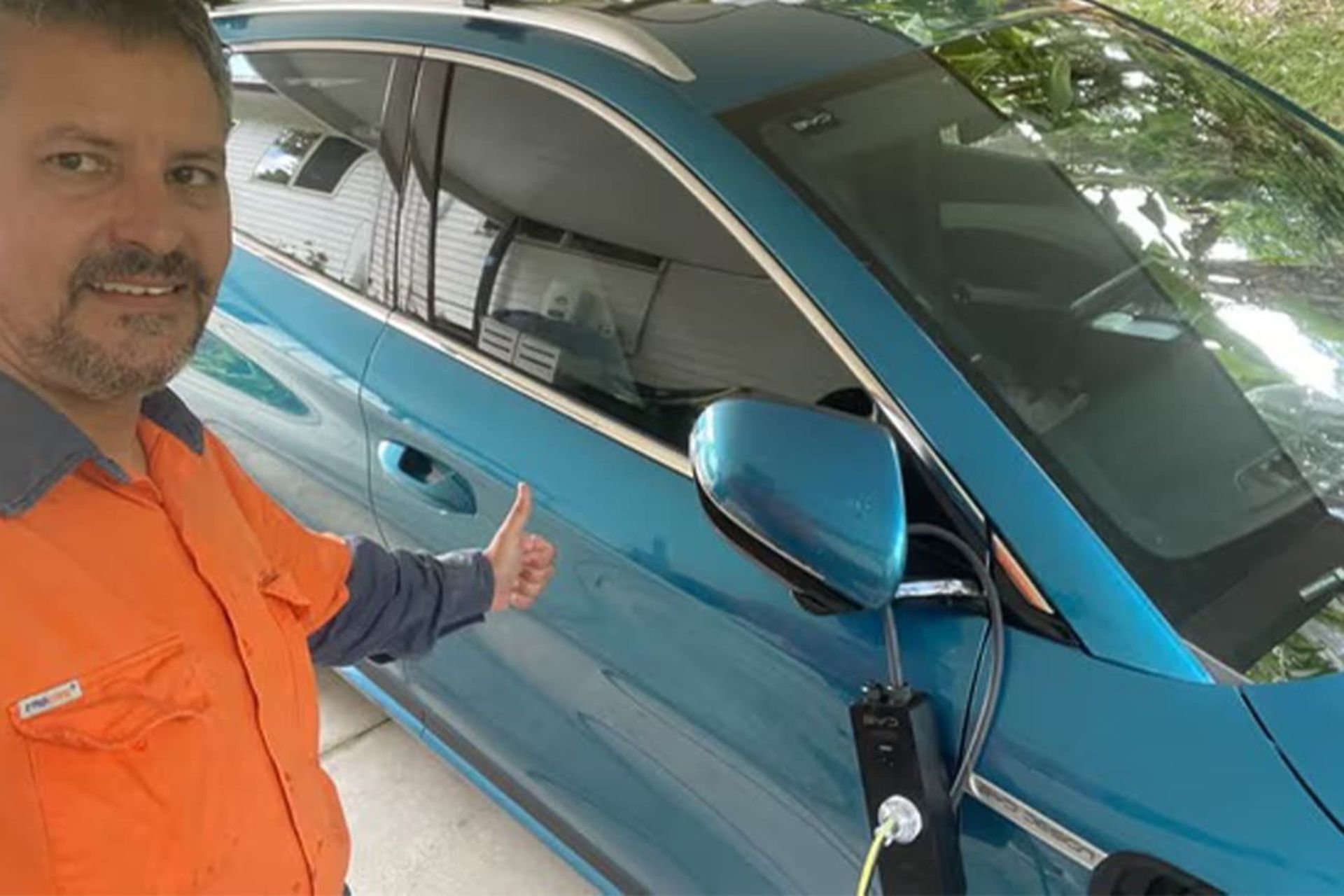 مردی خوشحال در کنار ماشین برقی آبی رنگ