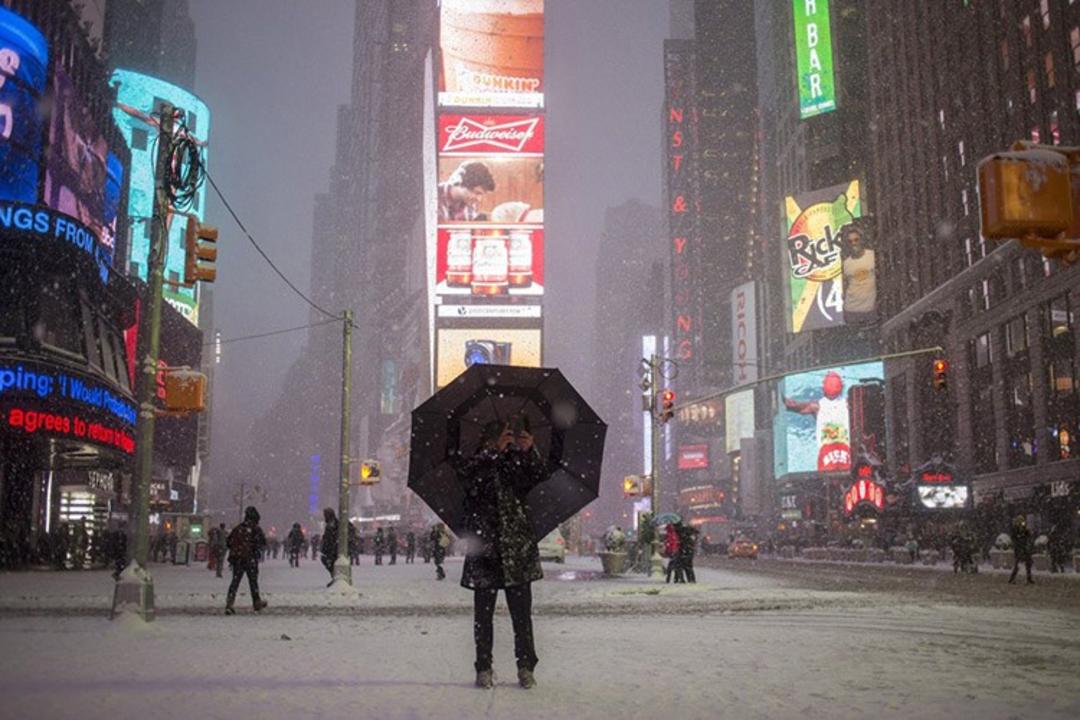 13 a man stands under an umbrella while photographing a snow storm in times square new york s f06c8