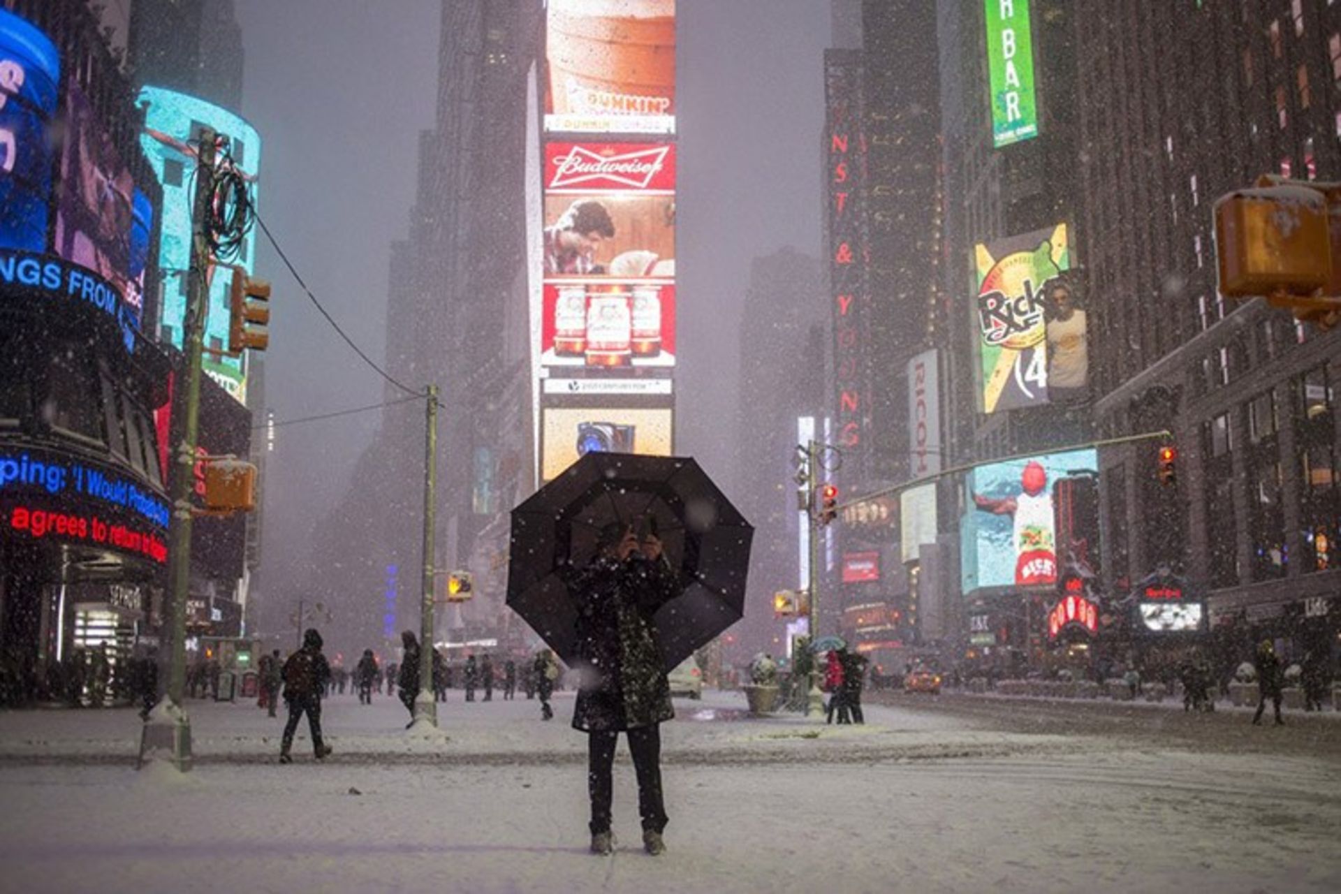 13 a man stands under an umbrella while photographing a snow storm in times square new york s f06c8