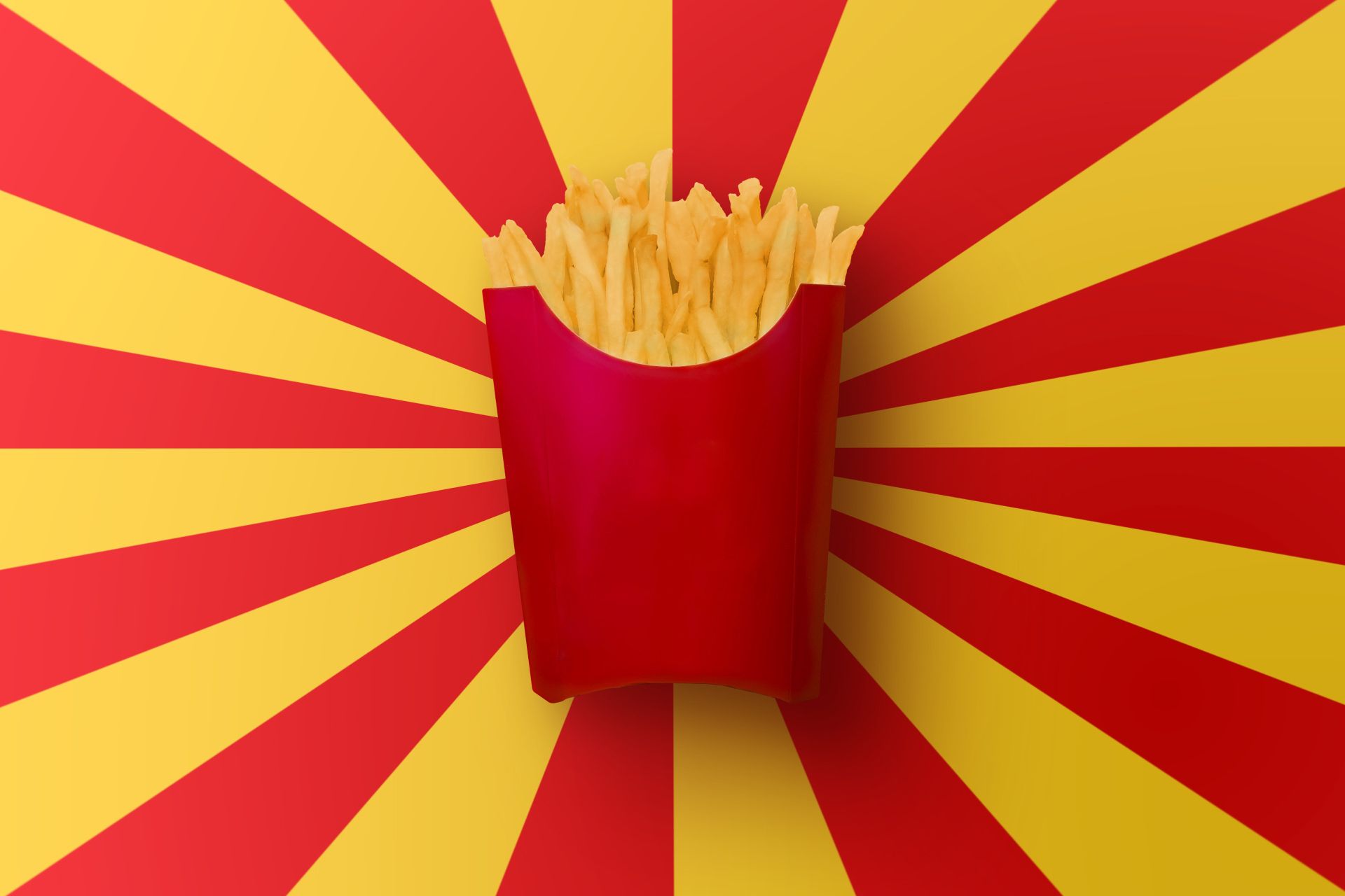 پاکت قرمز پر از سیب زمینی سرخ کرده در پس زمینه راه راه زرد و قرمز