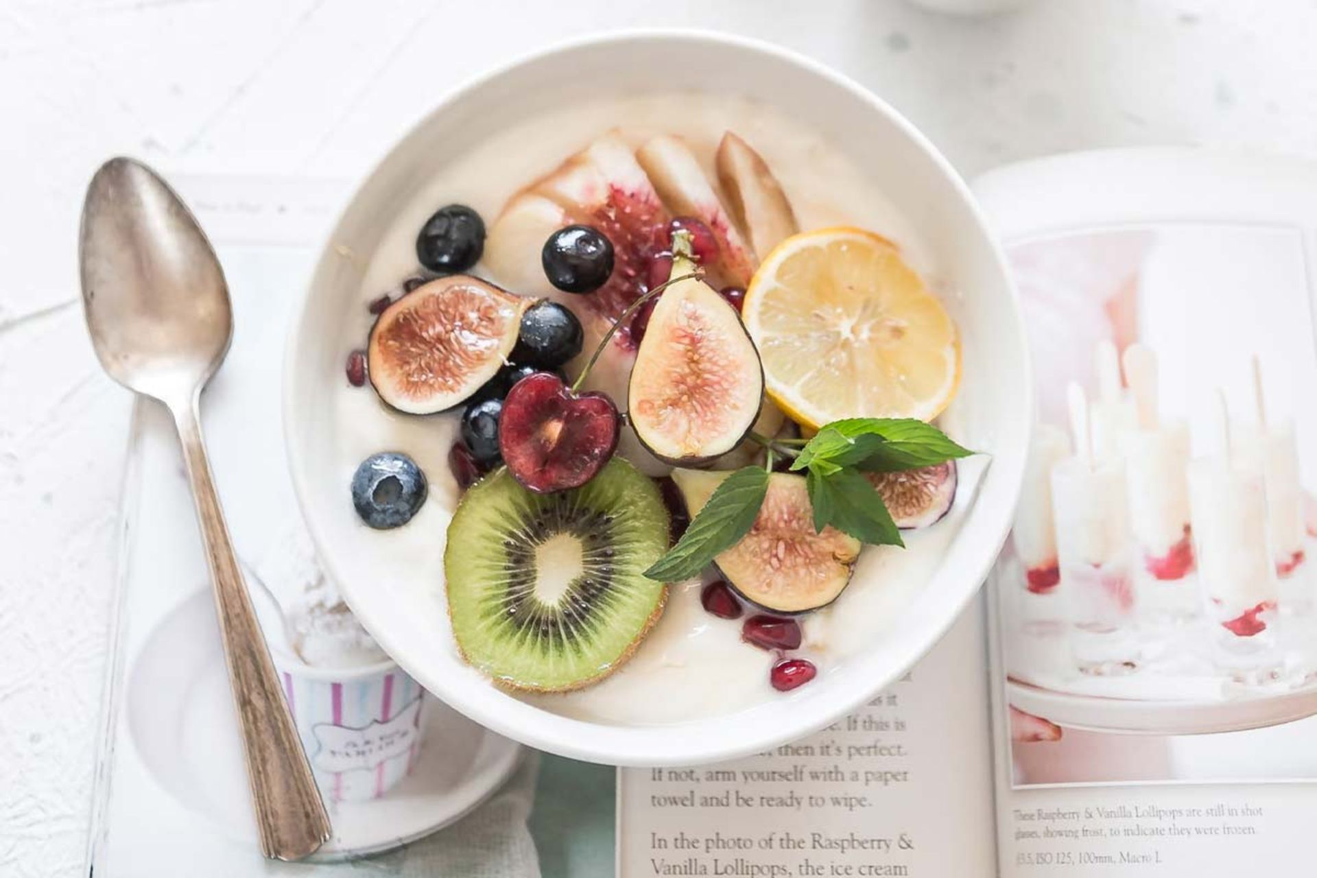 بشقاب سفید از میوه روی میز و قاشق کنار آن