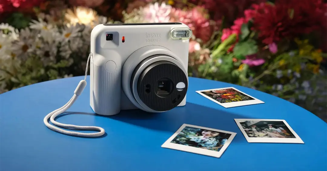 دوربین چاپ فوری اسکوئر ۲ (Instax Square 2) فوجی‌فیلم روی میز آبی