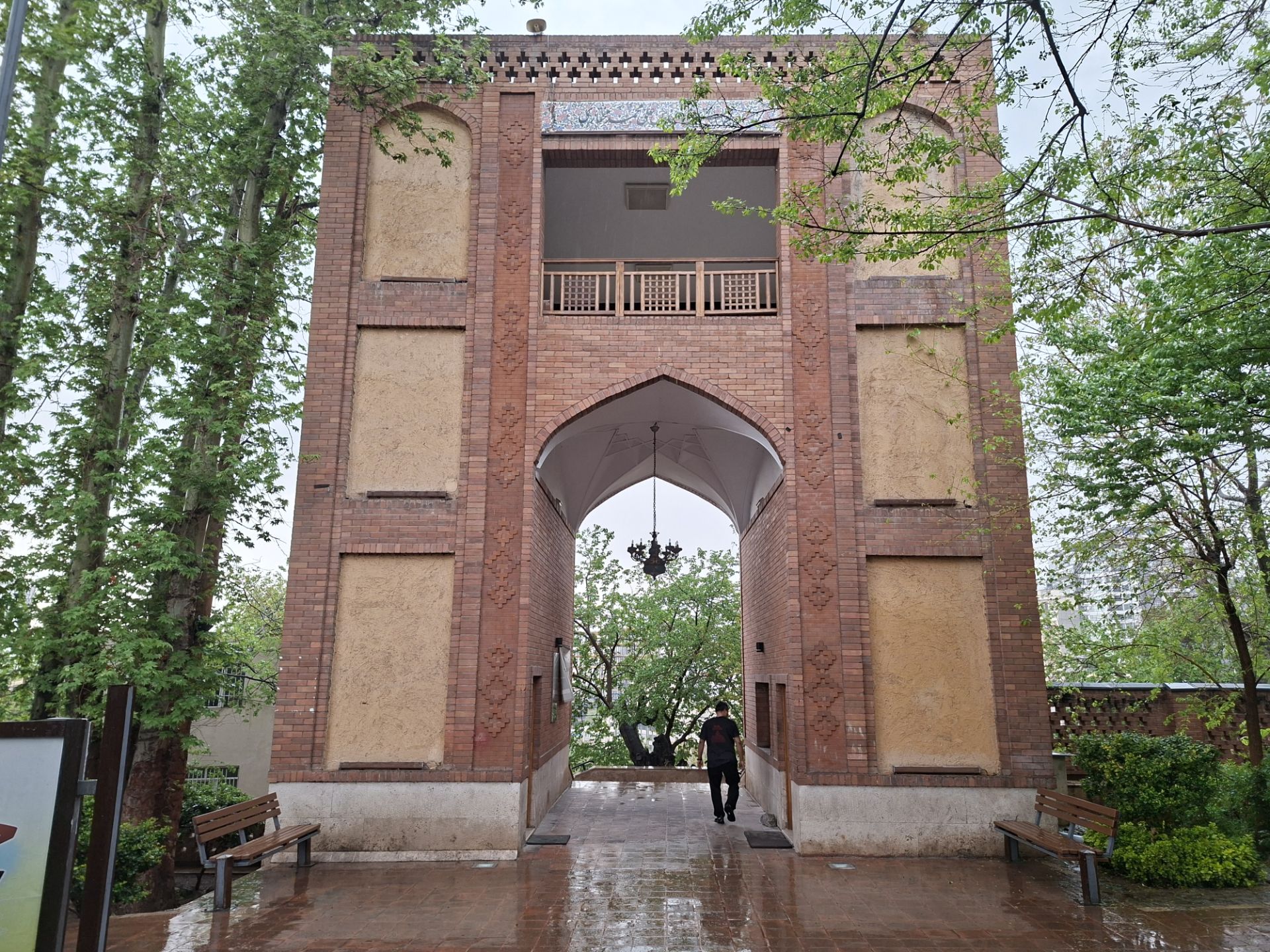 سردر آجری یک دروازه قدیمی در باغی با درختان سرسبز