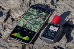 گجت ارتباط ماهواره‌ای inReach Mini 3 Plus روی کوه کنار گوشی آیفون