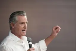 گوینت نیوسام (Gavin Newsom) فرماندار کالیفرنیا در حال صحبت با میکروفون
