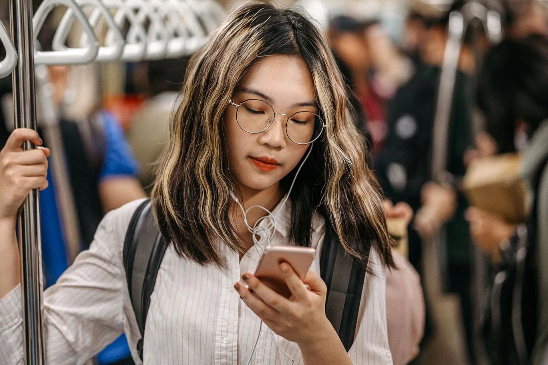 دختر جوان نسل زد در مترو درحال کار با گوشی با هندزفری