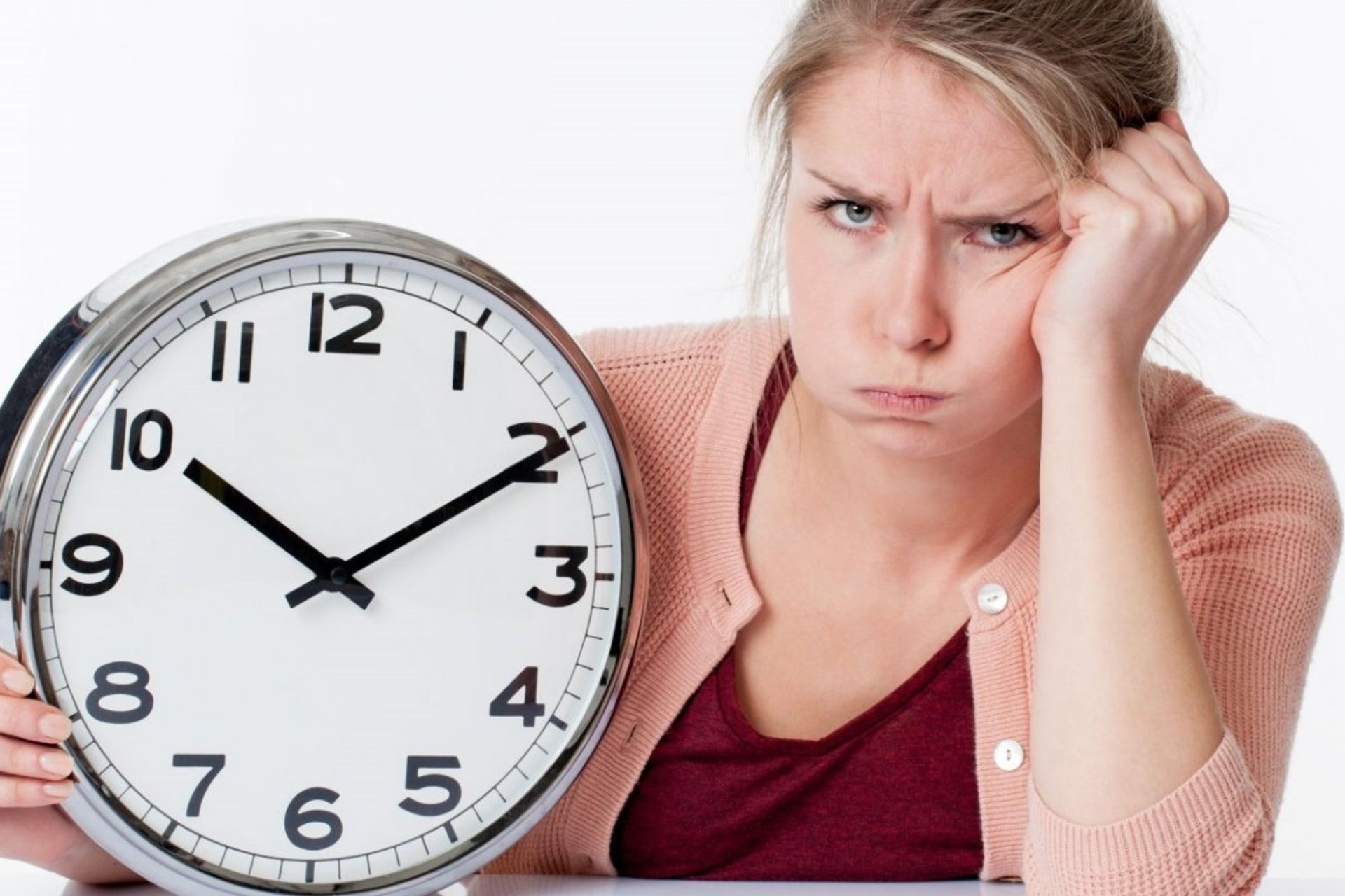 زن جوان و کلافه ساعت بزرگی را در دست گرفته است