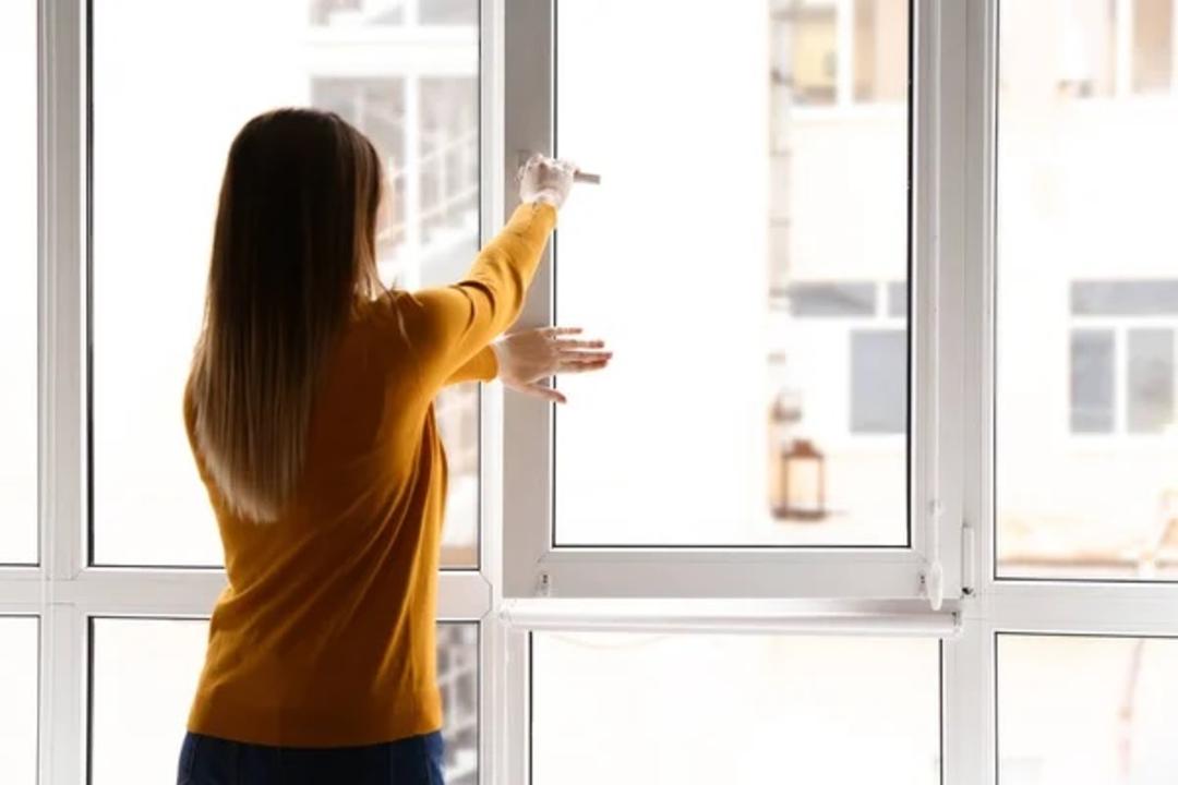 خانمی پنجره را می‌بندد