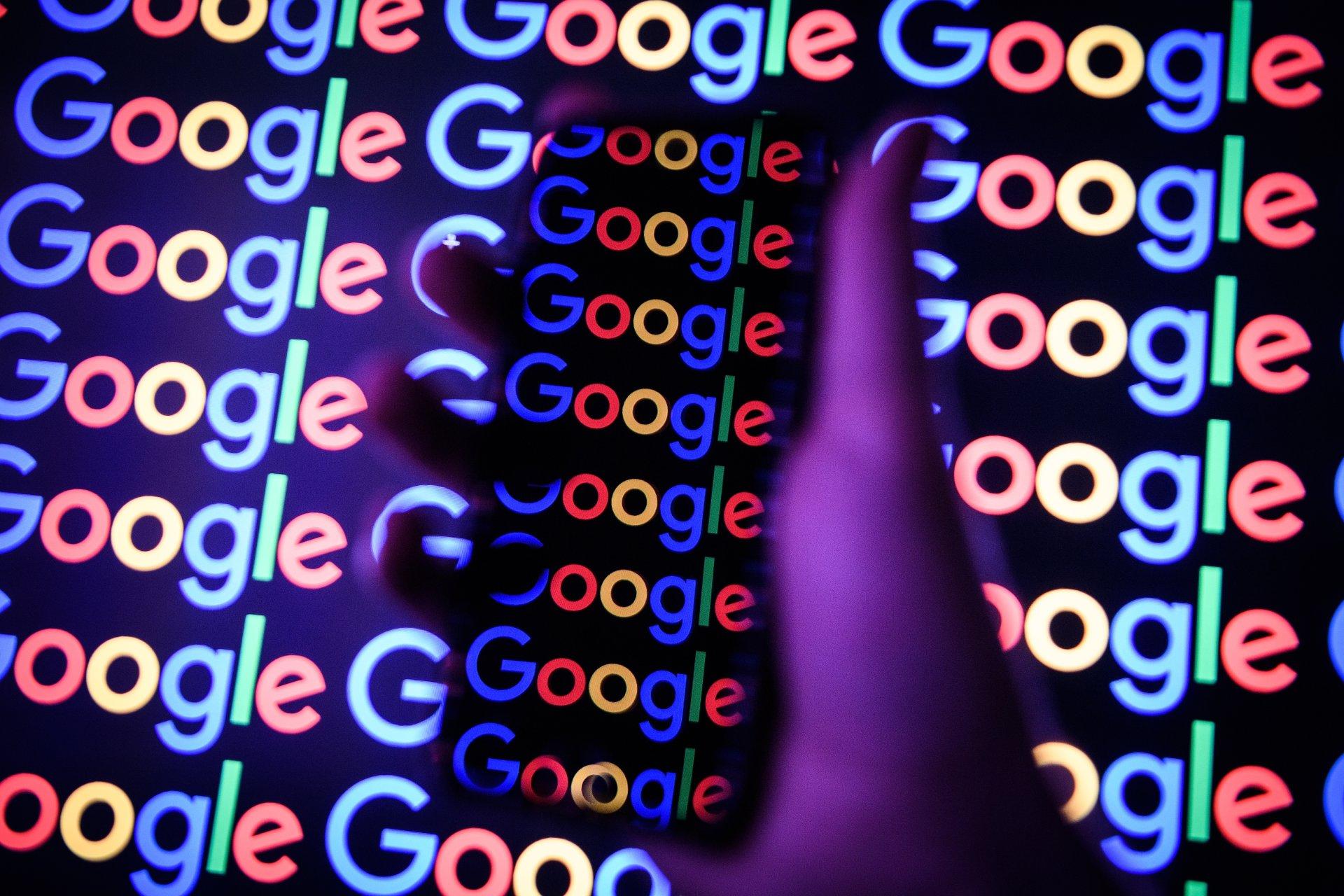 گوشی در دست با لوگو گوگل و پس زمینه لوگو گوگل