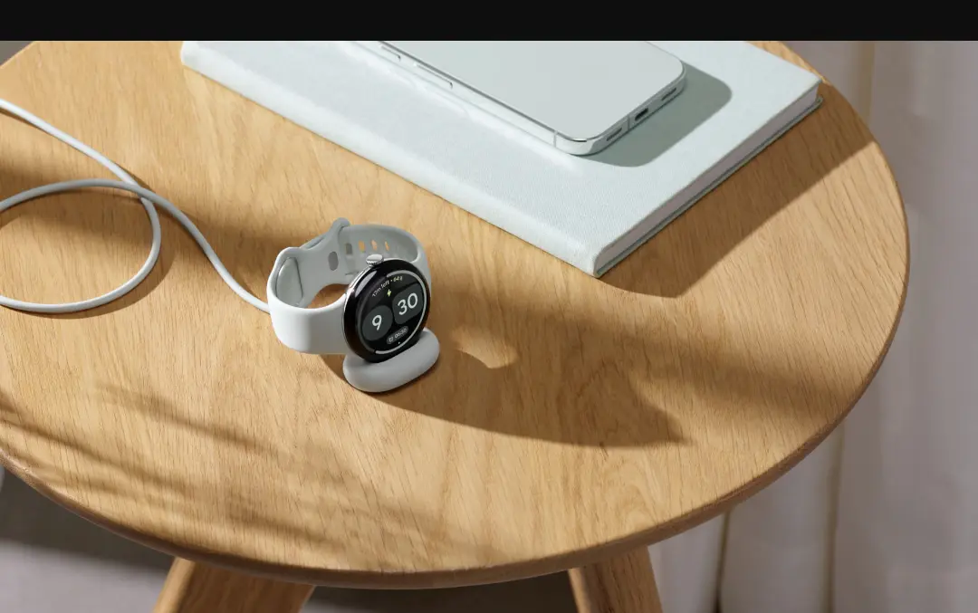 ساعت هوشمند گوگل (Google Smartwatch) روی میز چوبی در کنار گوشی و دفترچه