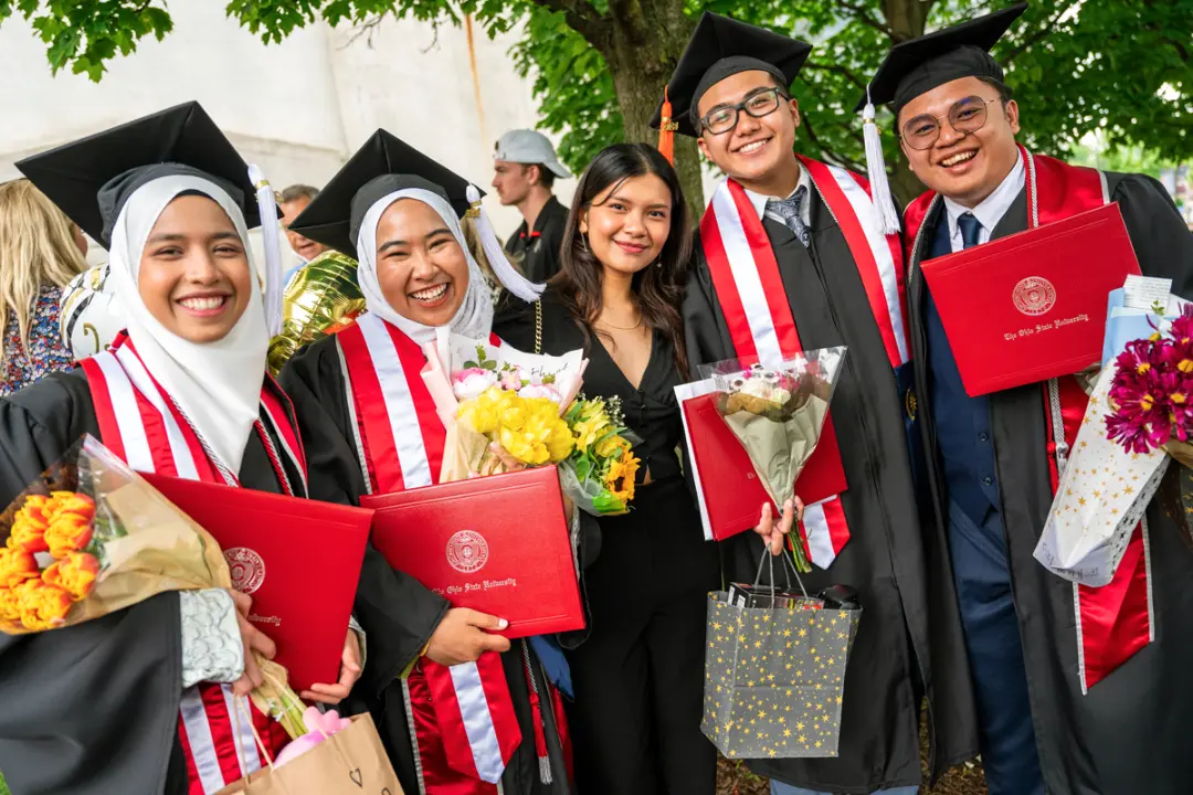 دانشجویان فارغ‌التحصیل (Graduates) با لباس‌های رسمی و کلاه فارغ‌التحصیلی در حال جشن گرفتن