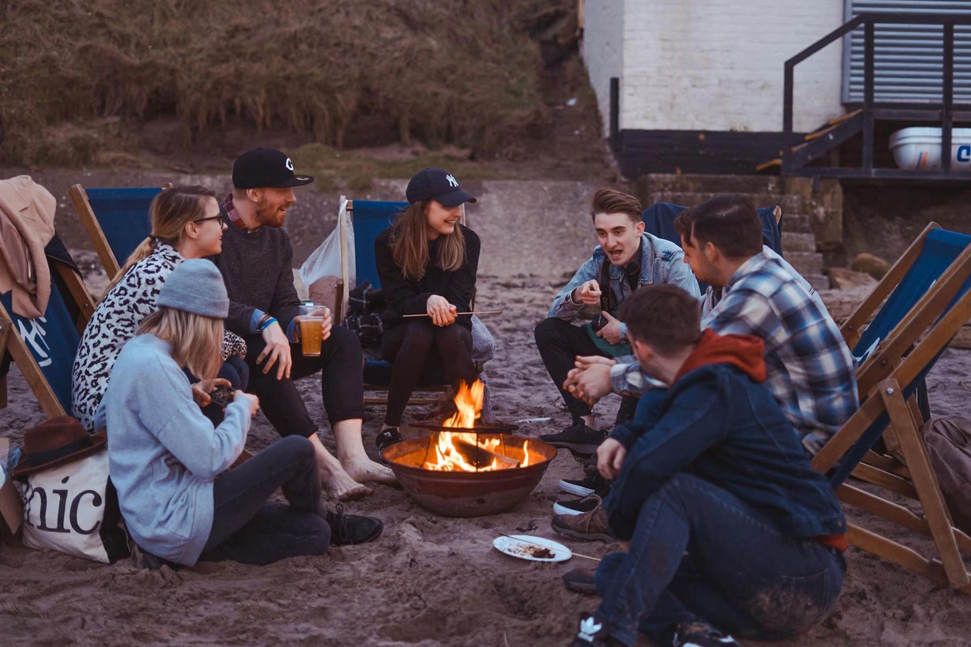 گروهی زن و مرد جوان دور یک آتش نشسته و در حال مکالمه و خنده