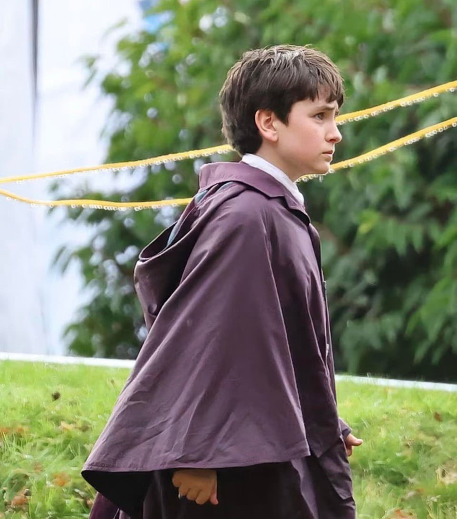 یک پسر نوجوان در پشت‌صحنه‌ی سریال هری پاتر با ردای بنفش