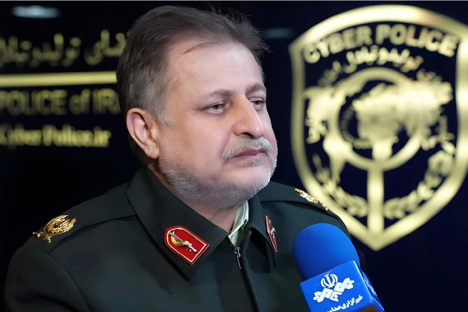 رئیس پلیس فتا در حال صحبت در مقابل نشان پلیس سایبری