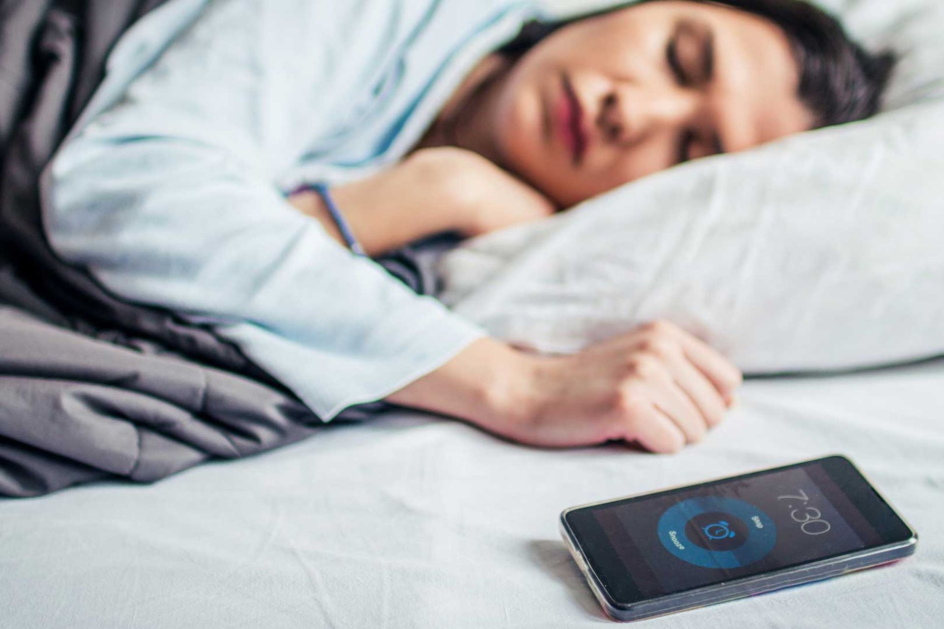 زن جوان درحال خواب و گوشی موبایل در کنار دست او