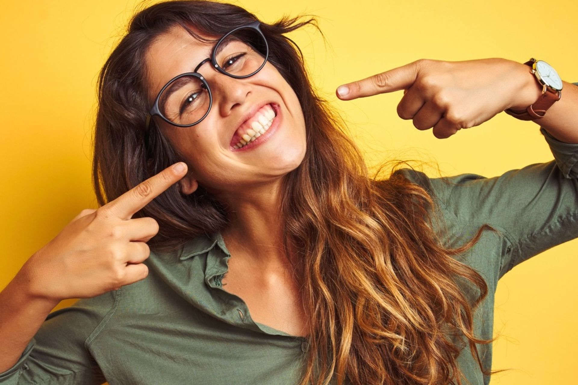 زن جوان با دست به لبخند خود اشاره می‌کند