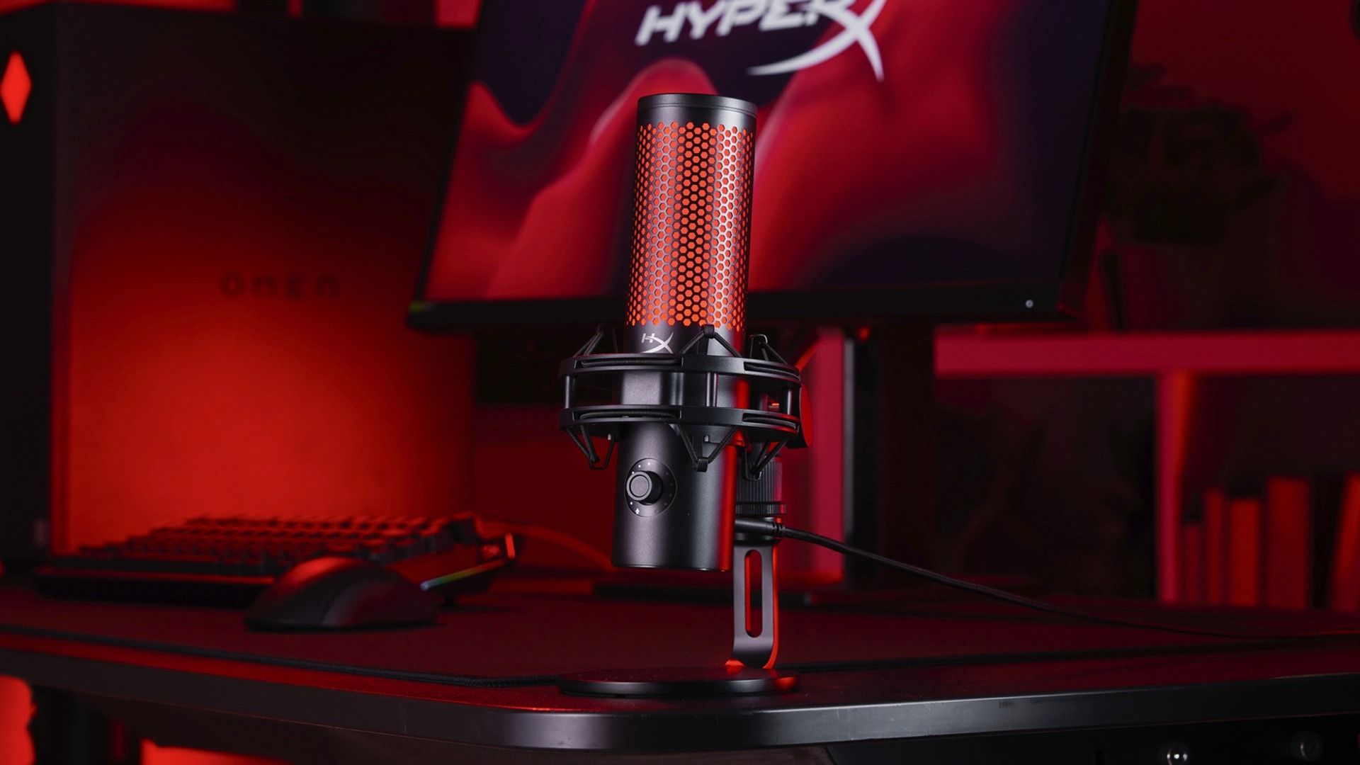 میکروفون گیمینگ اچ‌پی HyperX QuadCast 2 S روی میز در فضای اتاق با نور قرمز