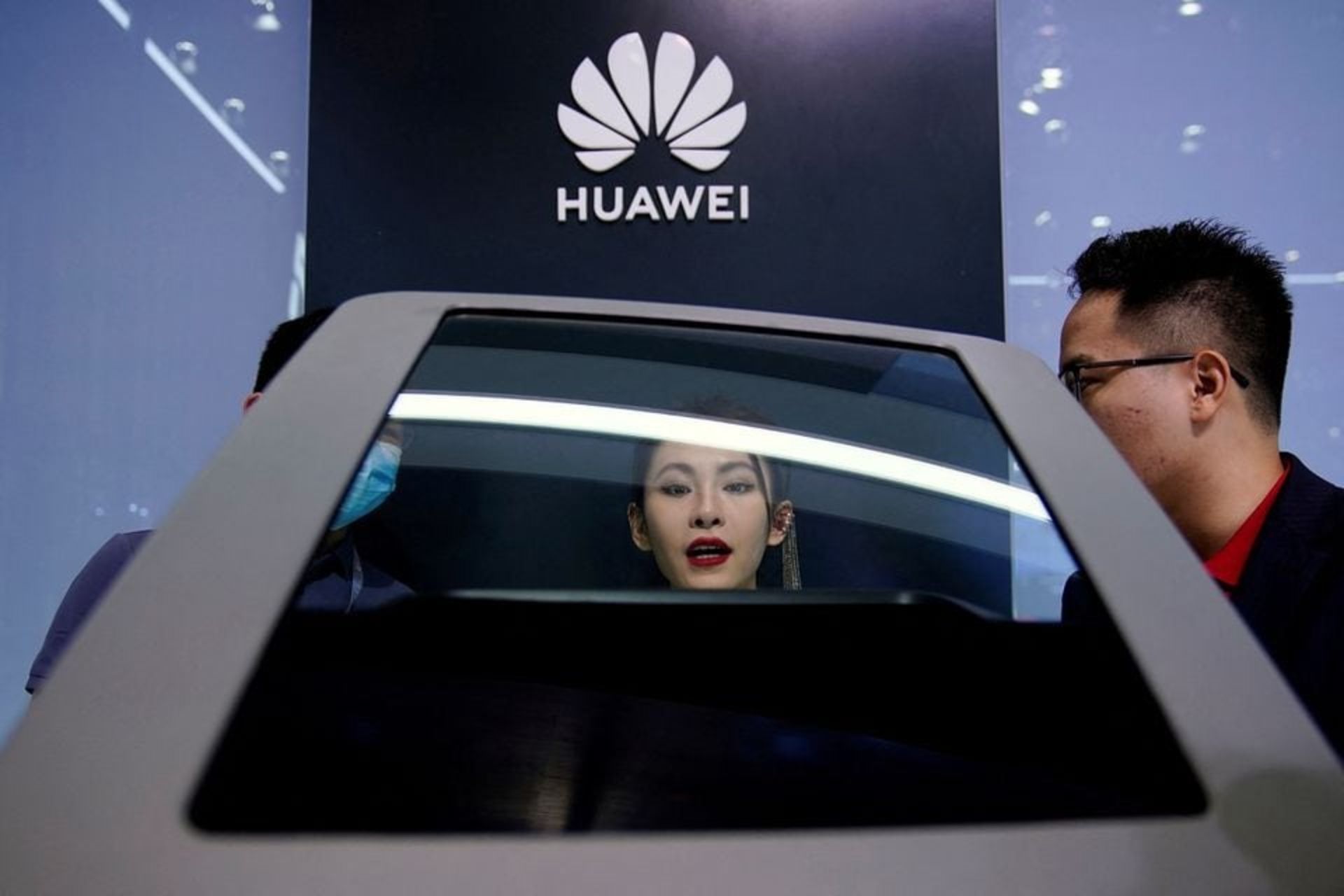 مرد و زن چینی در مقابل لوگوی هواوی در حال نگاه کردن به خودروی هوشمند