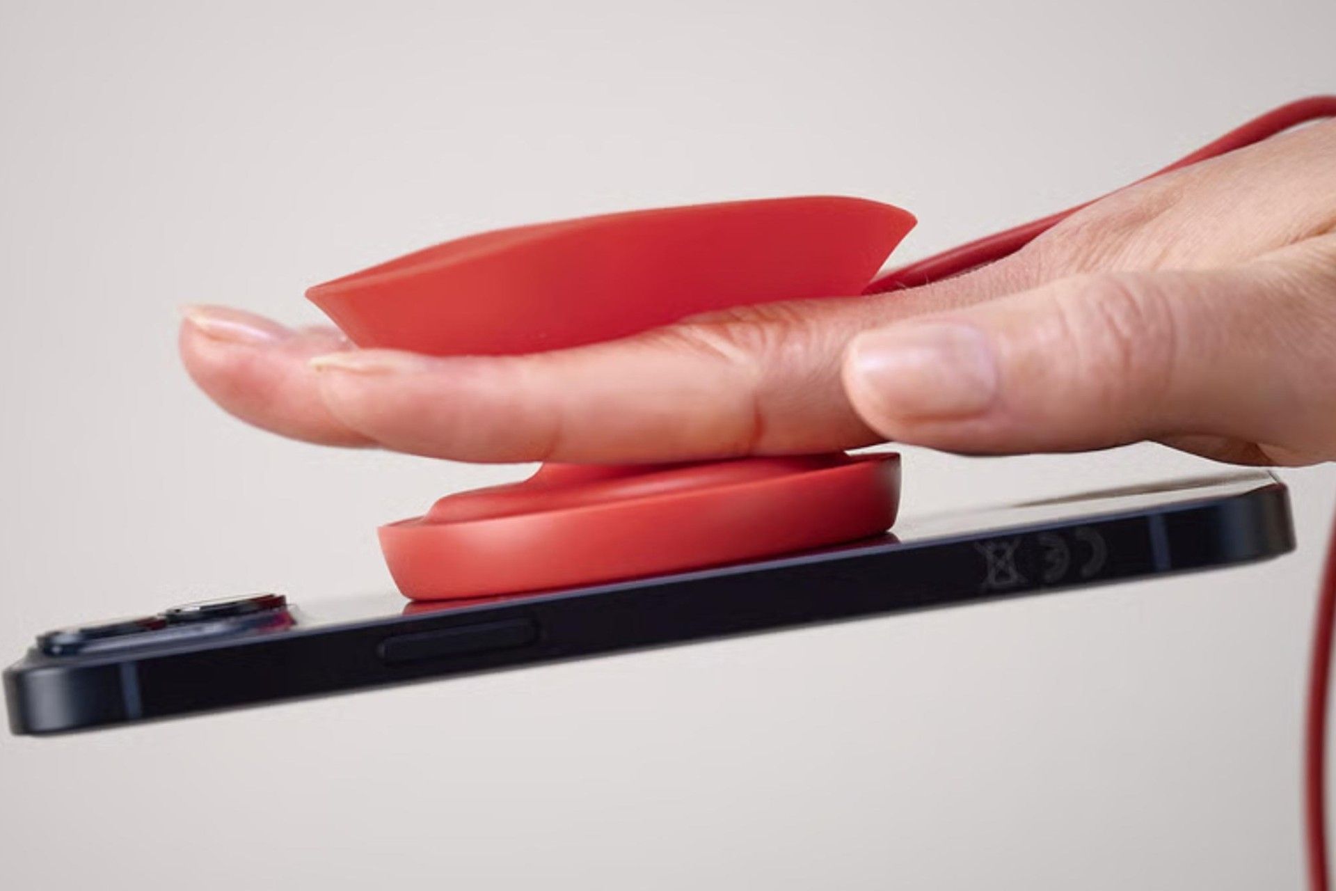 شارژر بی‌سیم IKEA و گوشی آیفون در دست از نمای نزدیک