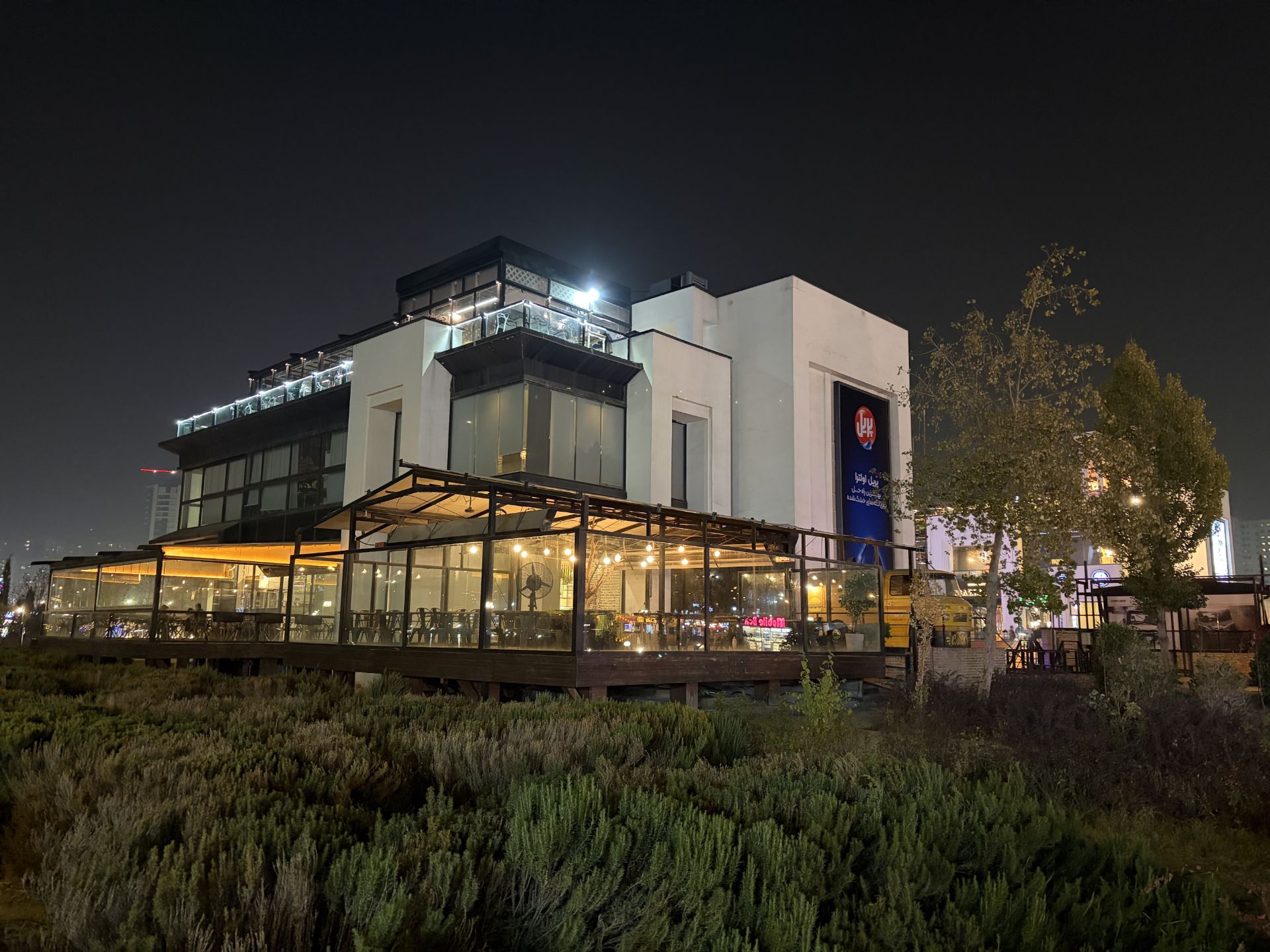 مرکز خرید چندطبقه مدرن در شب با تابلوهای روشن فروشگاه‌ها