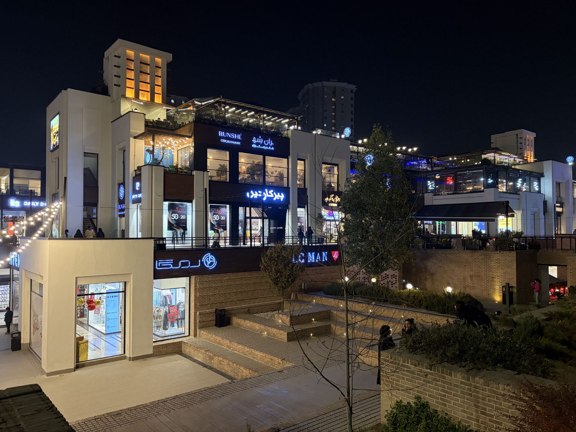 رستوران چندطبقه با تراس شیشه‌ای و نور زرد گرم در شب