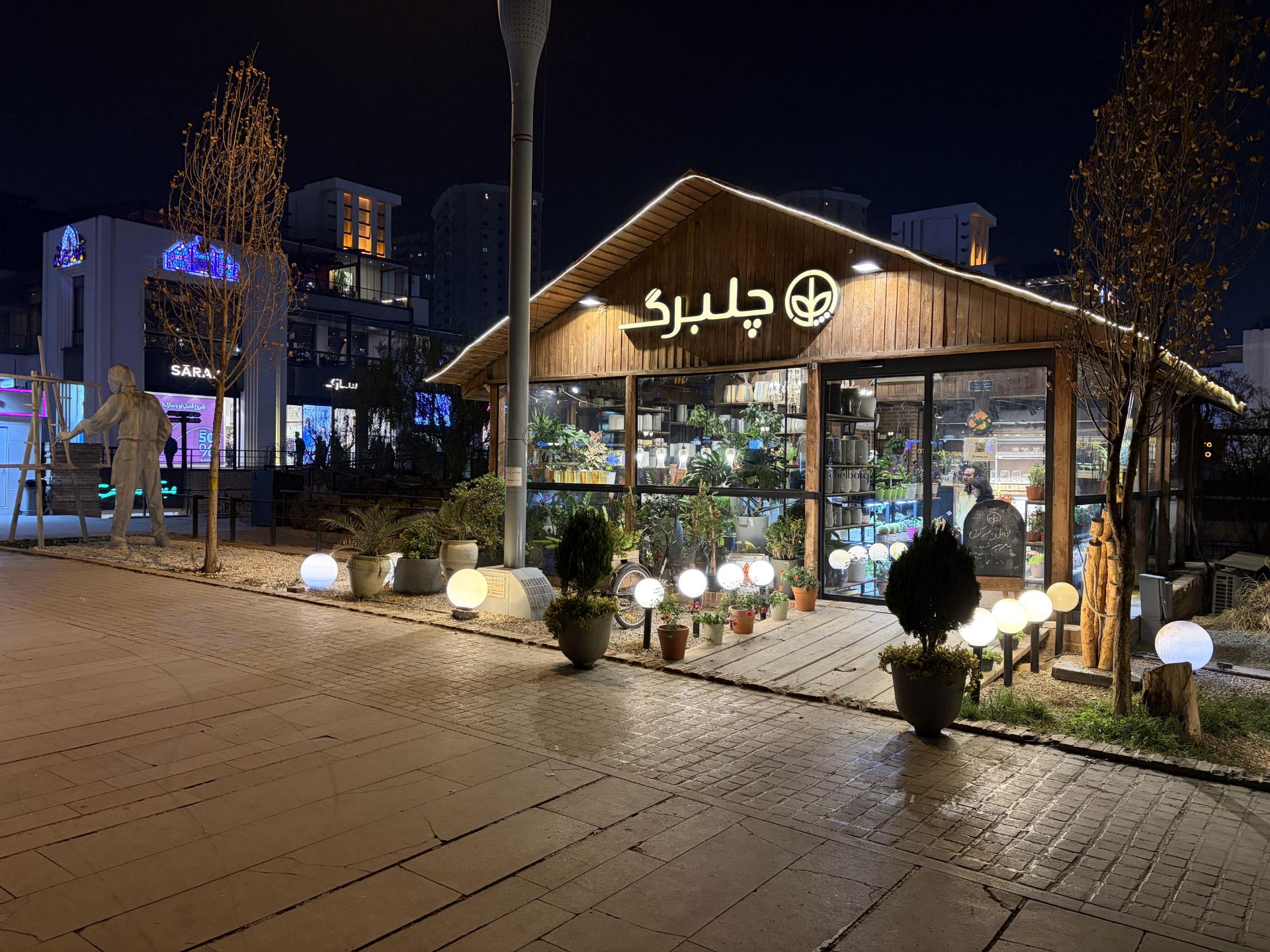 گل‌فروشی با نمای چوبی و تابلوی «چلبرگ» در شب