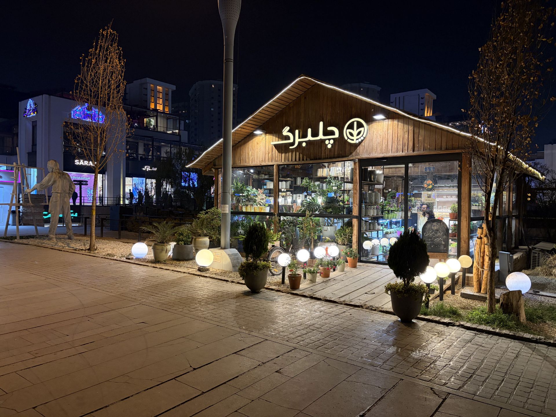 گل‌فروشی با نمای چوبی و تابلوی «چلبرگ» در شب