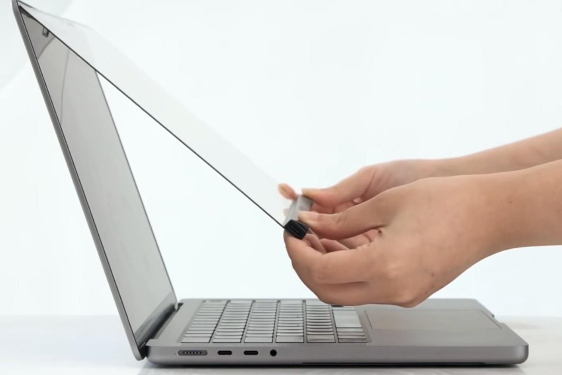 شخصی در حال چسباندن لایه‌ی لمسی به مک‌بوک اپل