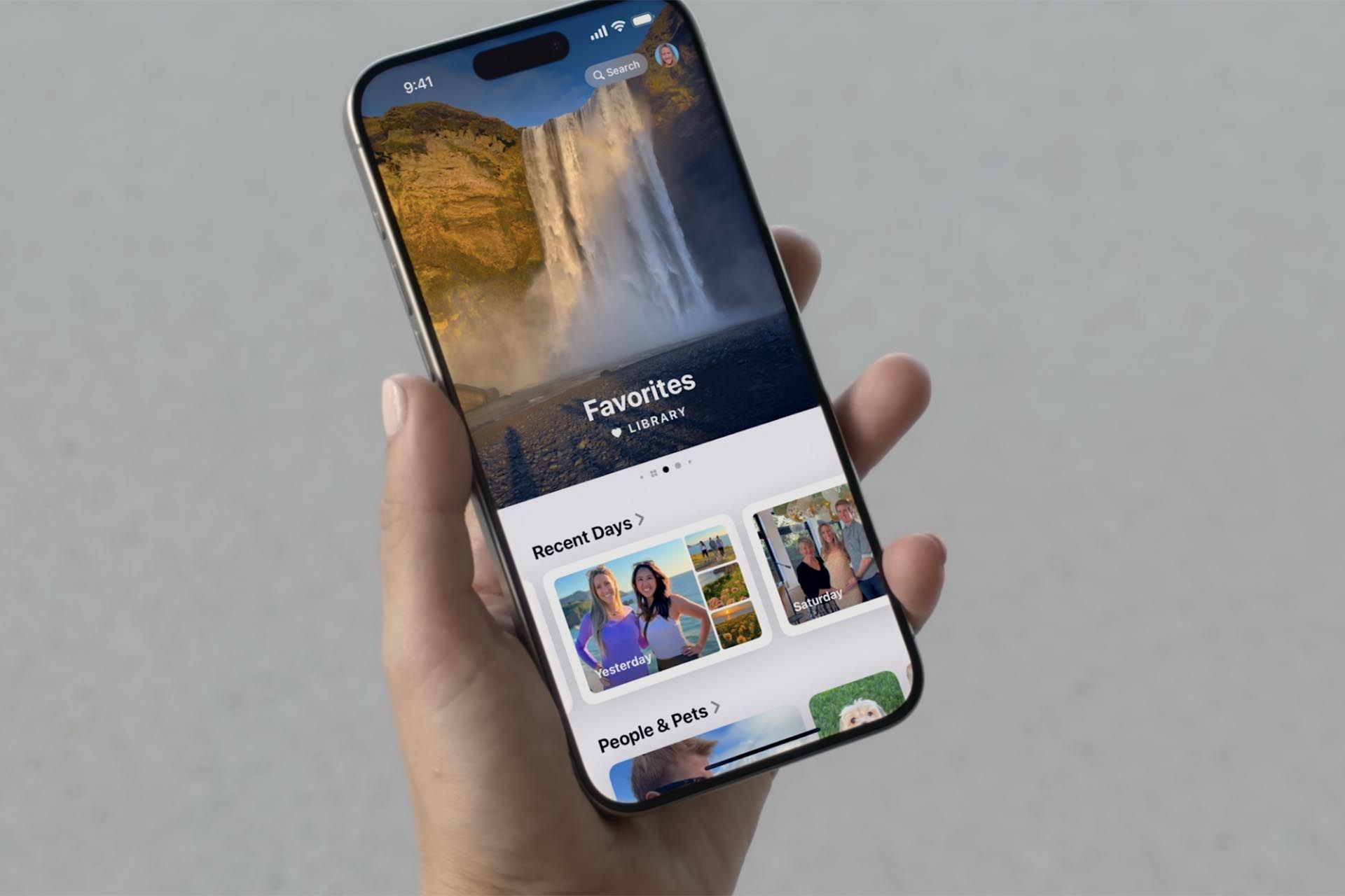 یک گوشی آيفون  با اپلیکیشن Photos - با اسلاید بزرگ در بالای صفحه و دسته‌بندی‌های مختلف پایین صفحه در دست یک نفر