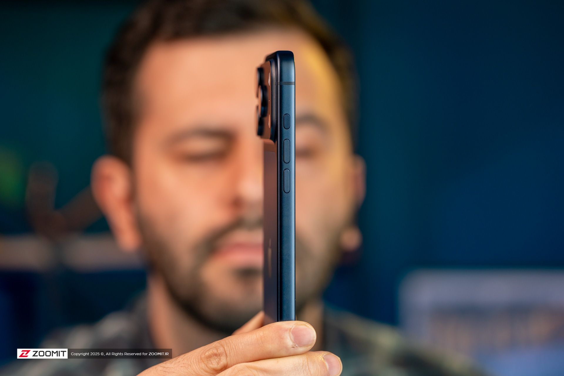 نیم رخ گوشی آیفون ۱۷ پرو مکس / iPhone 17 Pro Max دربرابر صورت مرد جوان ریشی