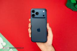 مدل آبی آیفون ۱۷ پرو مکس / iPhone 17 Pro Max در دست پس زمینه قرمز