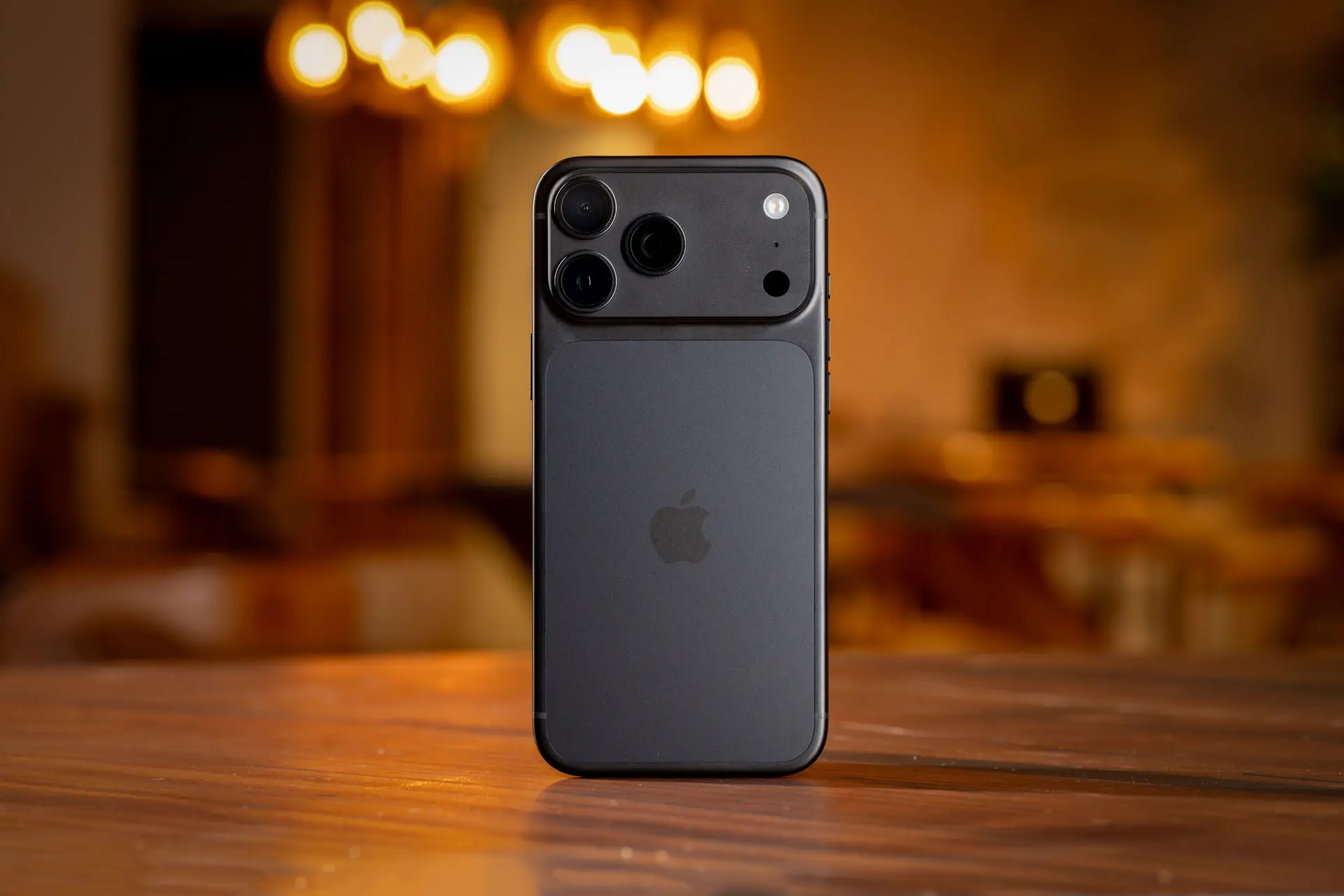 گوشی آیفون ۱۸ پرو مکس (iPhone 18 Pro Max) با بدنه تیره روی میز چوبی