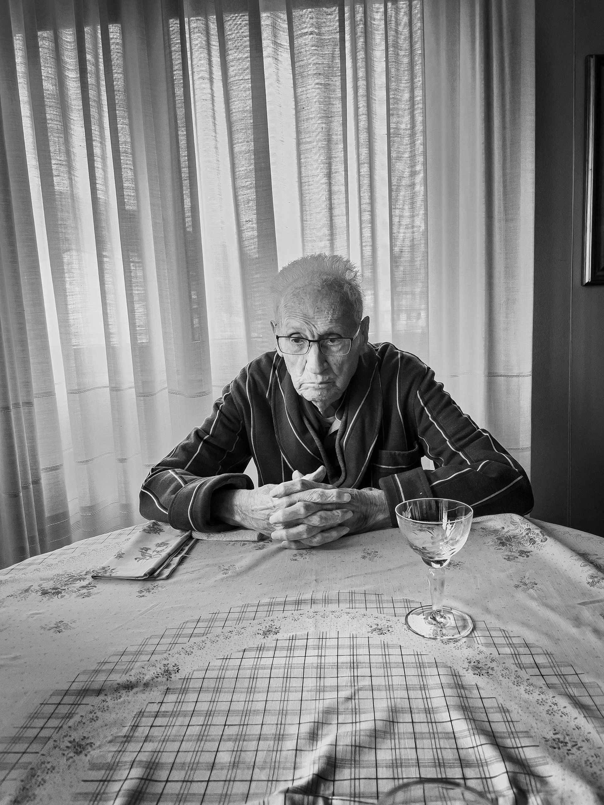 پیرمرد نشسته با میز جلوش و دست هایش روی میز