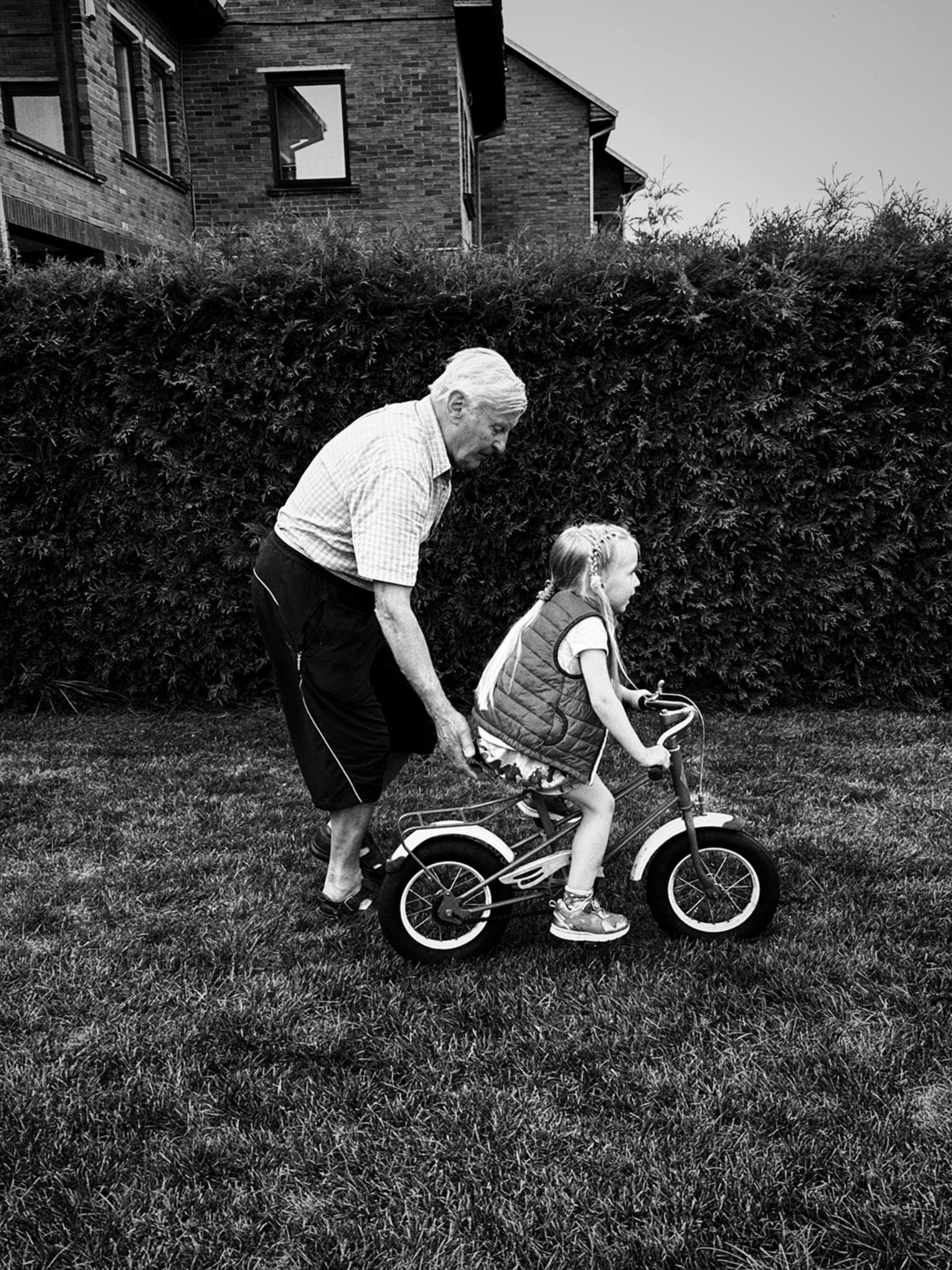 پیرمرد درحال هل دادن دختربچه روی دوچرخه