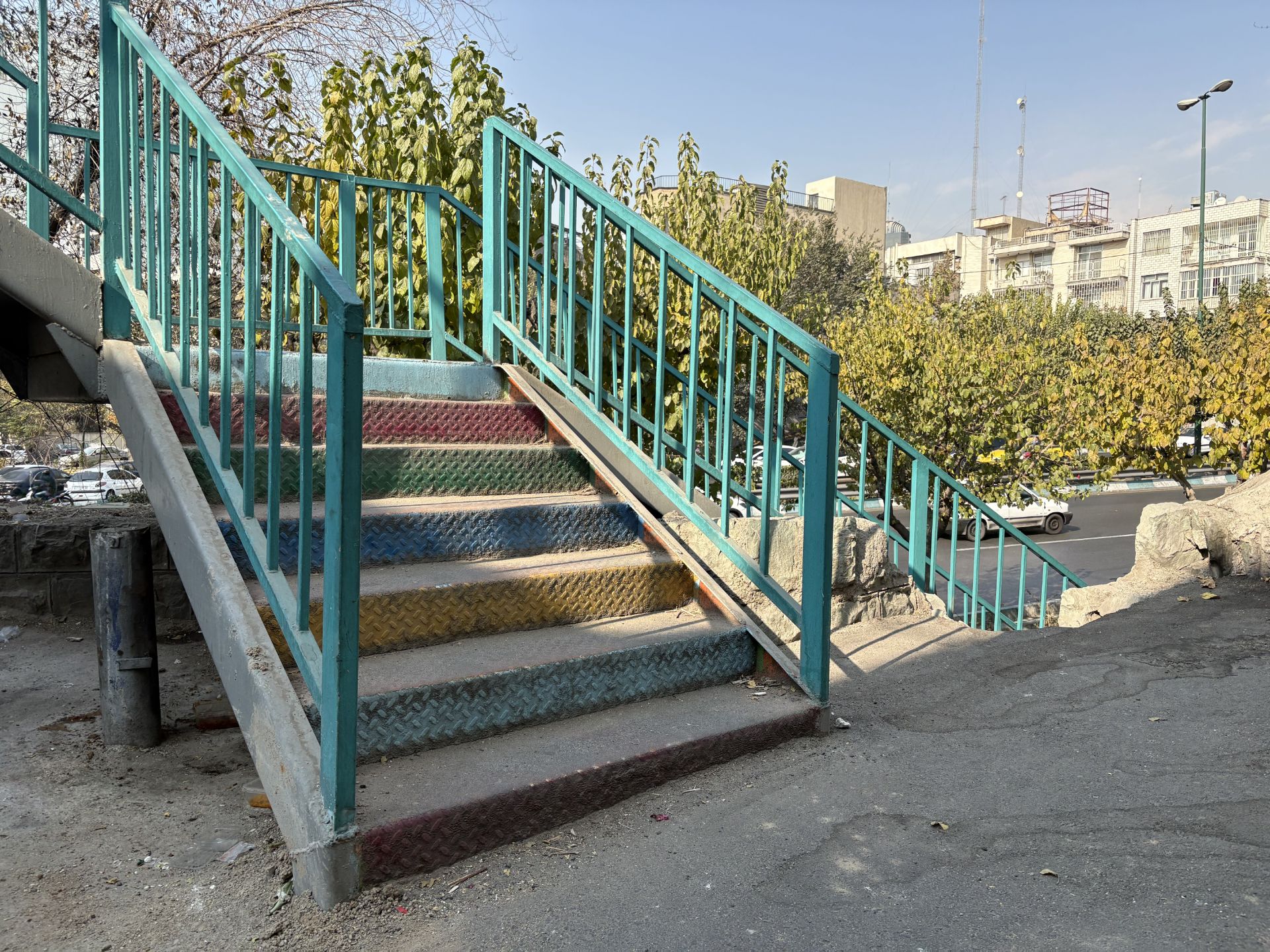 عکس پله‌های رنگی و نرده‌های سبز در نور روز با دوربین اصلی آیفون ۱۶