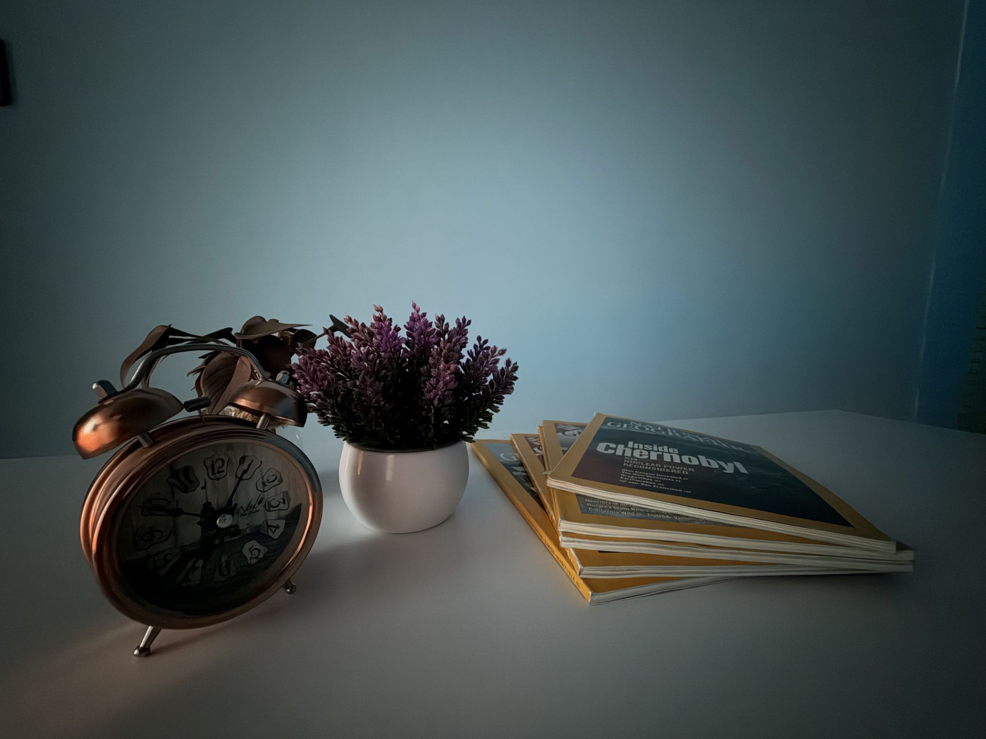 نمونه عکس دوربین اولتراواید آیفون ۱۷ در نور کم (چیدمان ساعت و مجله)