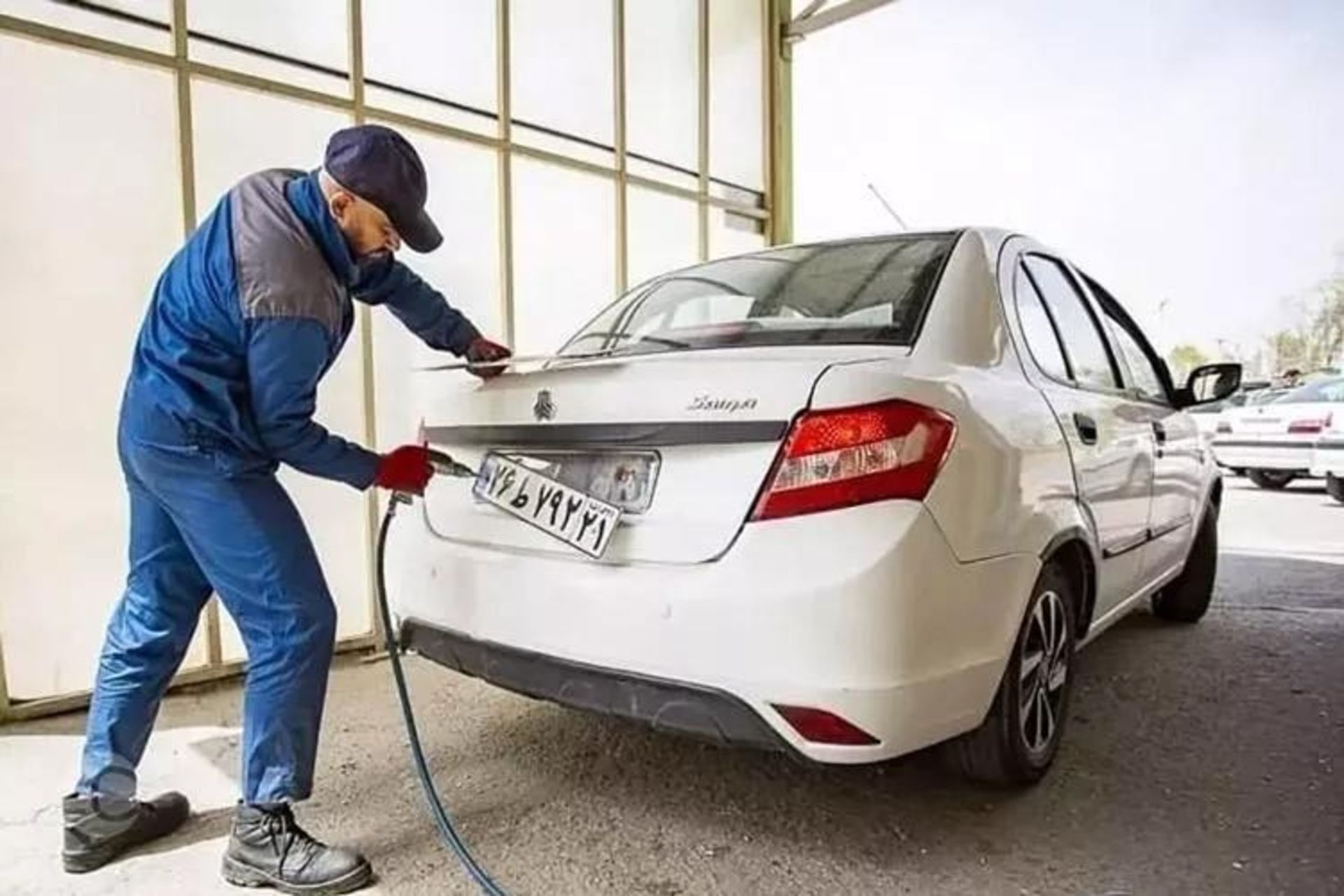 یک مرد در حال فک پلاک خودرو سفید