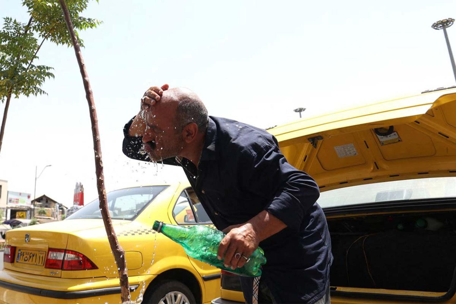 راننده تاکسی درحال ریختن آب روی صورت خود در اوج گرمای روزانه