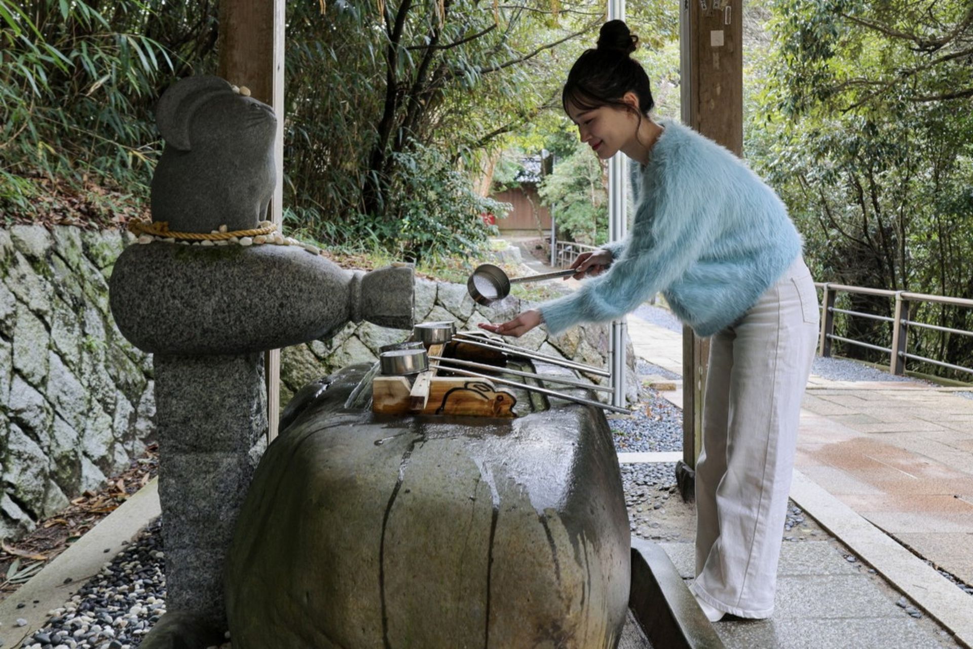 دختری ژاپنی پیش از ورود به معبد دستانش را می‌شوید